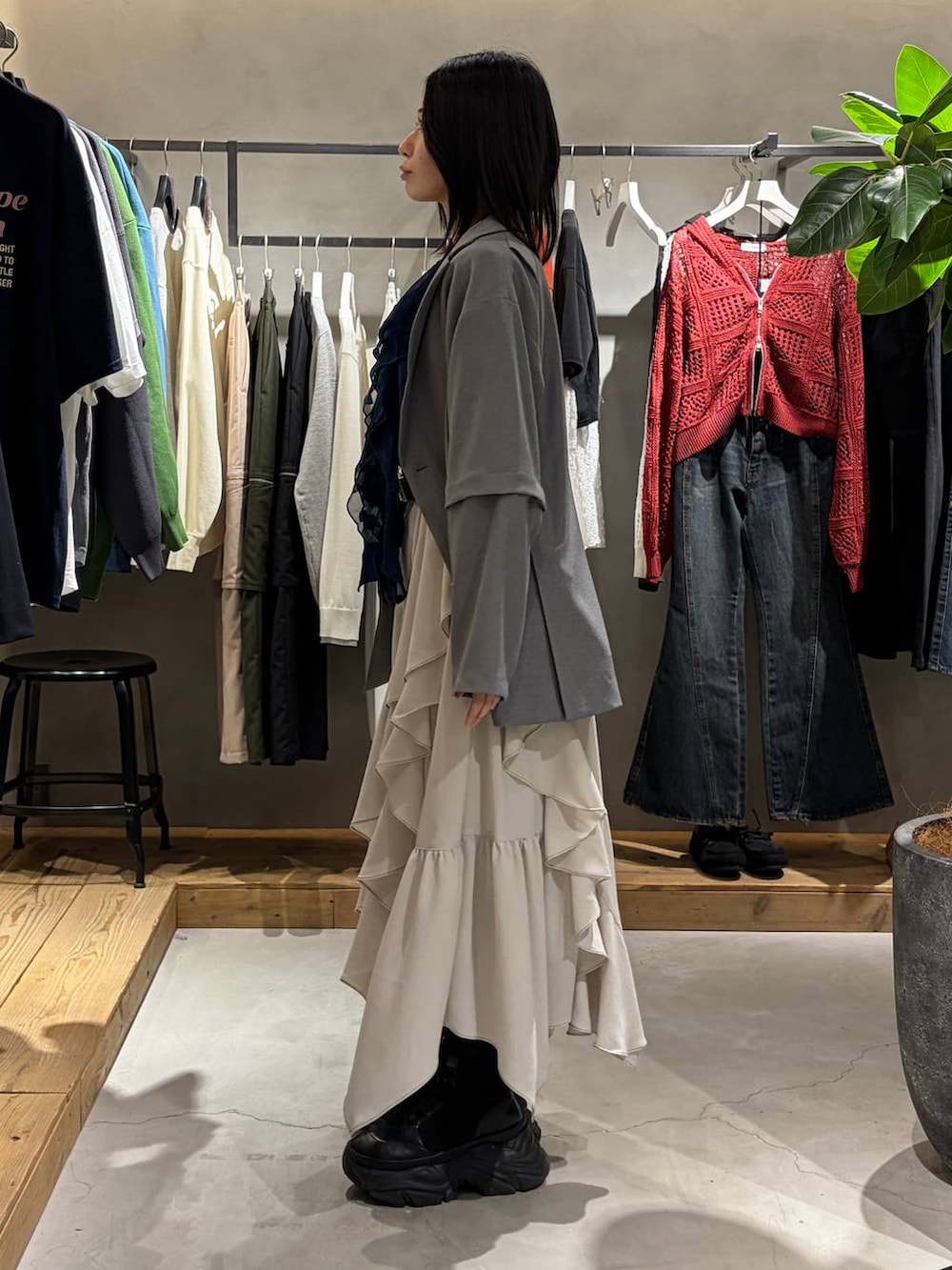 ブラック系のブーツ、ベージュ系のスカート、グレー系のテーラードジャケットを着用したレディースの春コーディネートの2枚目の写真