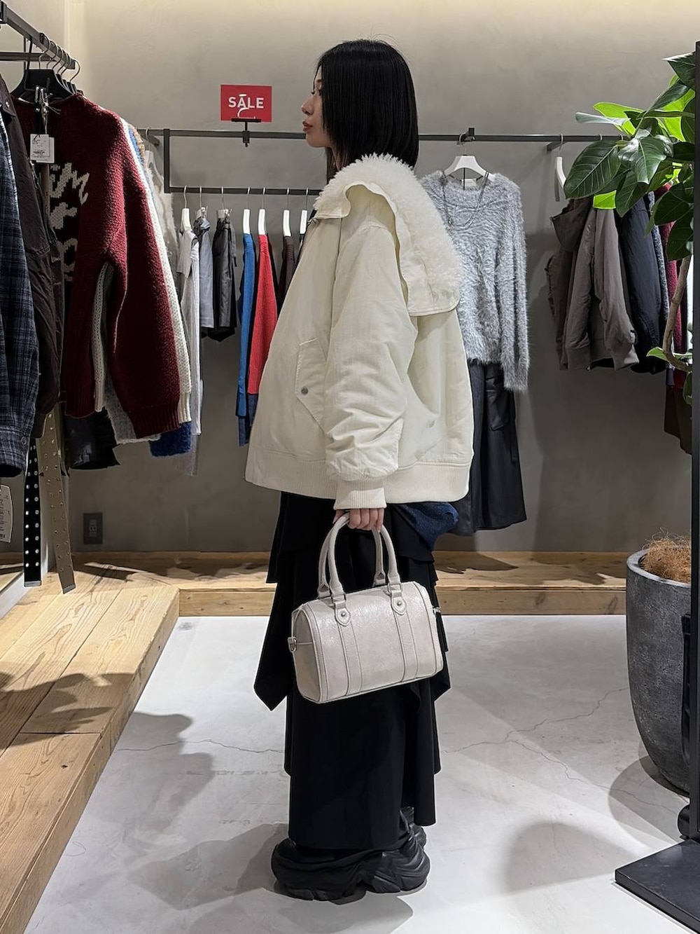 ホワイト系のブルゾン、ホワイト系のTシャツ/カットソー、ブラック系のスカートを着用したレディースの冬コーディネートの2枚目の写真