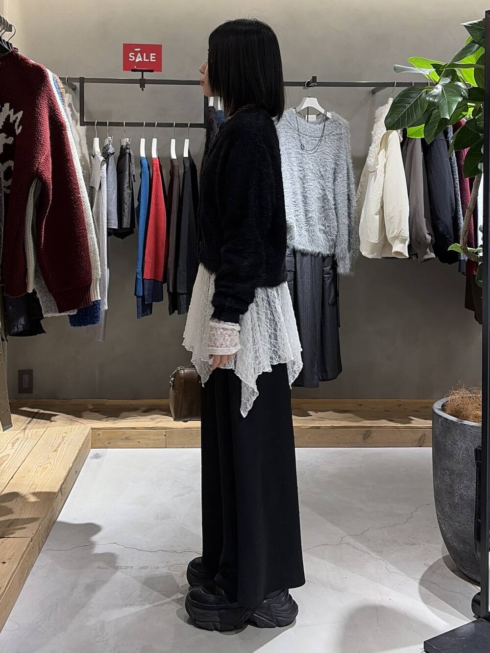 ブラック系のスカート、ブラウン系のボストンバッグ、ホワイト系のチュニックを着用したレディースの冬コーディネートの2枚目の写真