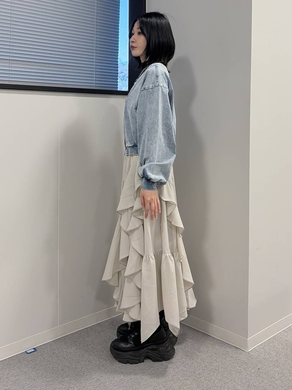 ブラック系のブーツ、ブラック系のニット/セーター、ベージュ系のスカートを着用したレディースの冬コーディネートの2枚目の写真