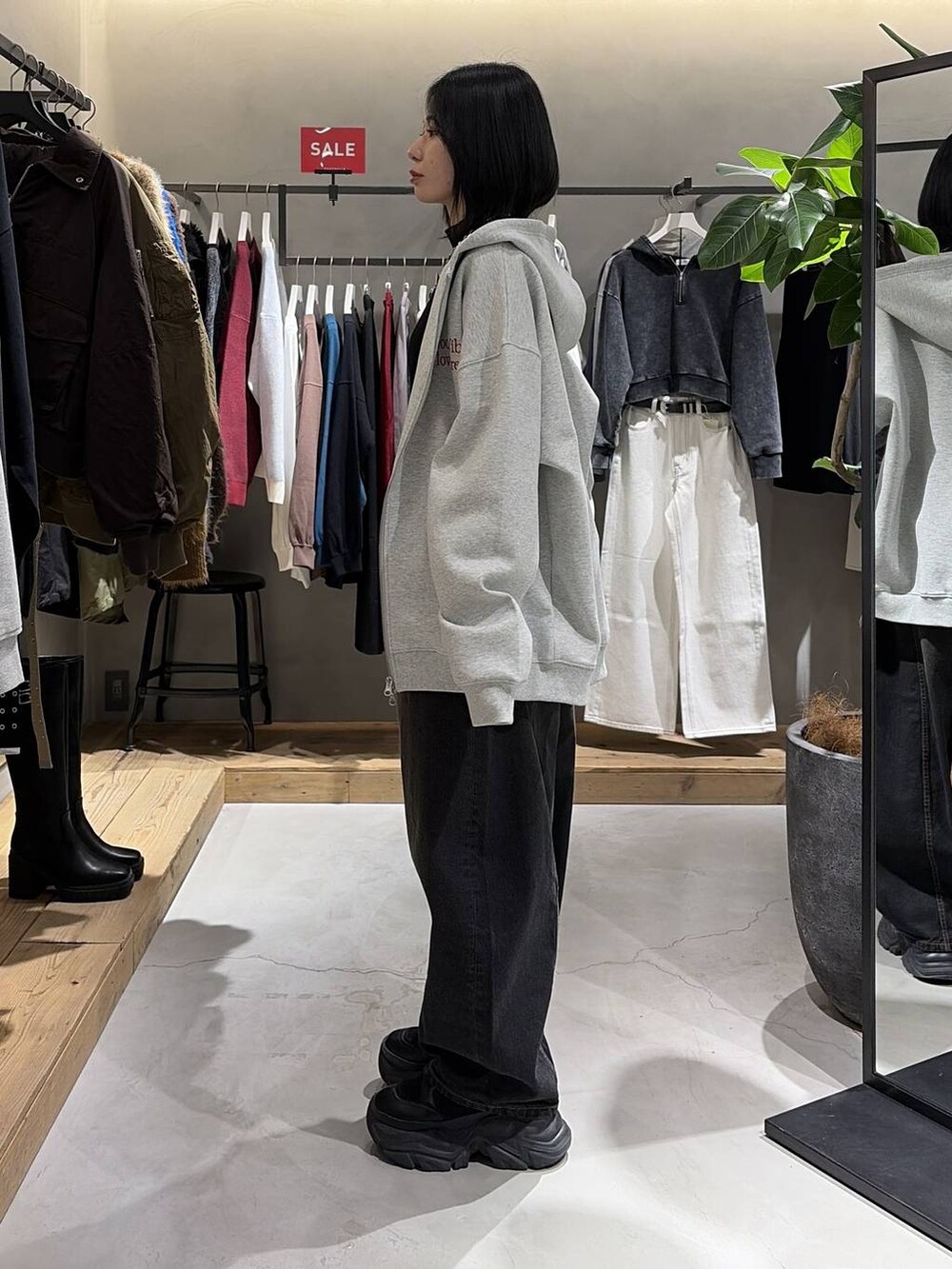 ブラック系のブーツ、グレー系のパーカー、ブラック系のデニムパンツを着用したレディースの冬コーディネートの2枚目の写真