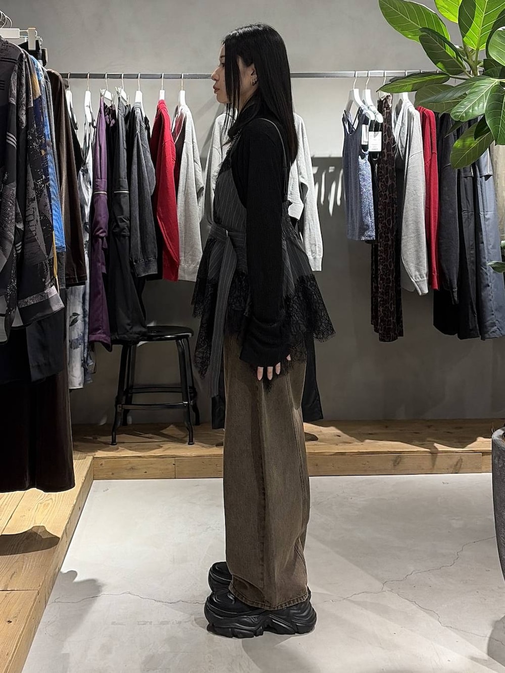 ブラウン系のデニムパンツ、ブラック系のスニーカー、ブラック系のニット/セーターを着用したレディースの夏コーディネートの2枚目の写真