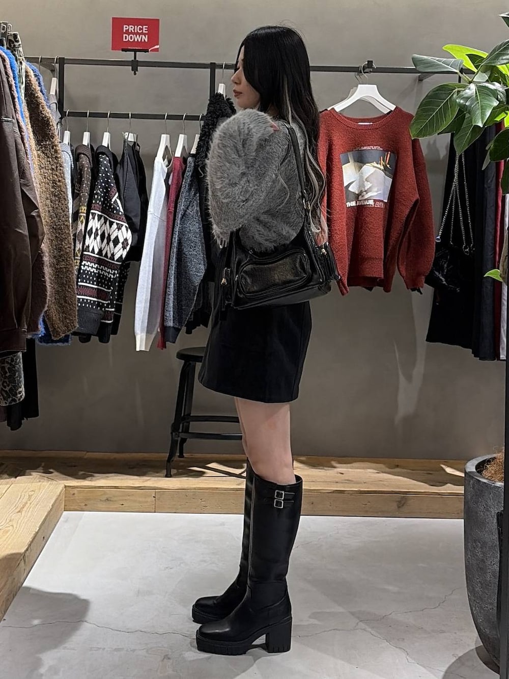 ブラック系のブーツ、ブラック系のスカート、ブラック系のショルダーバッグを着用したレディースの冬コーディネートの2枚目の写真