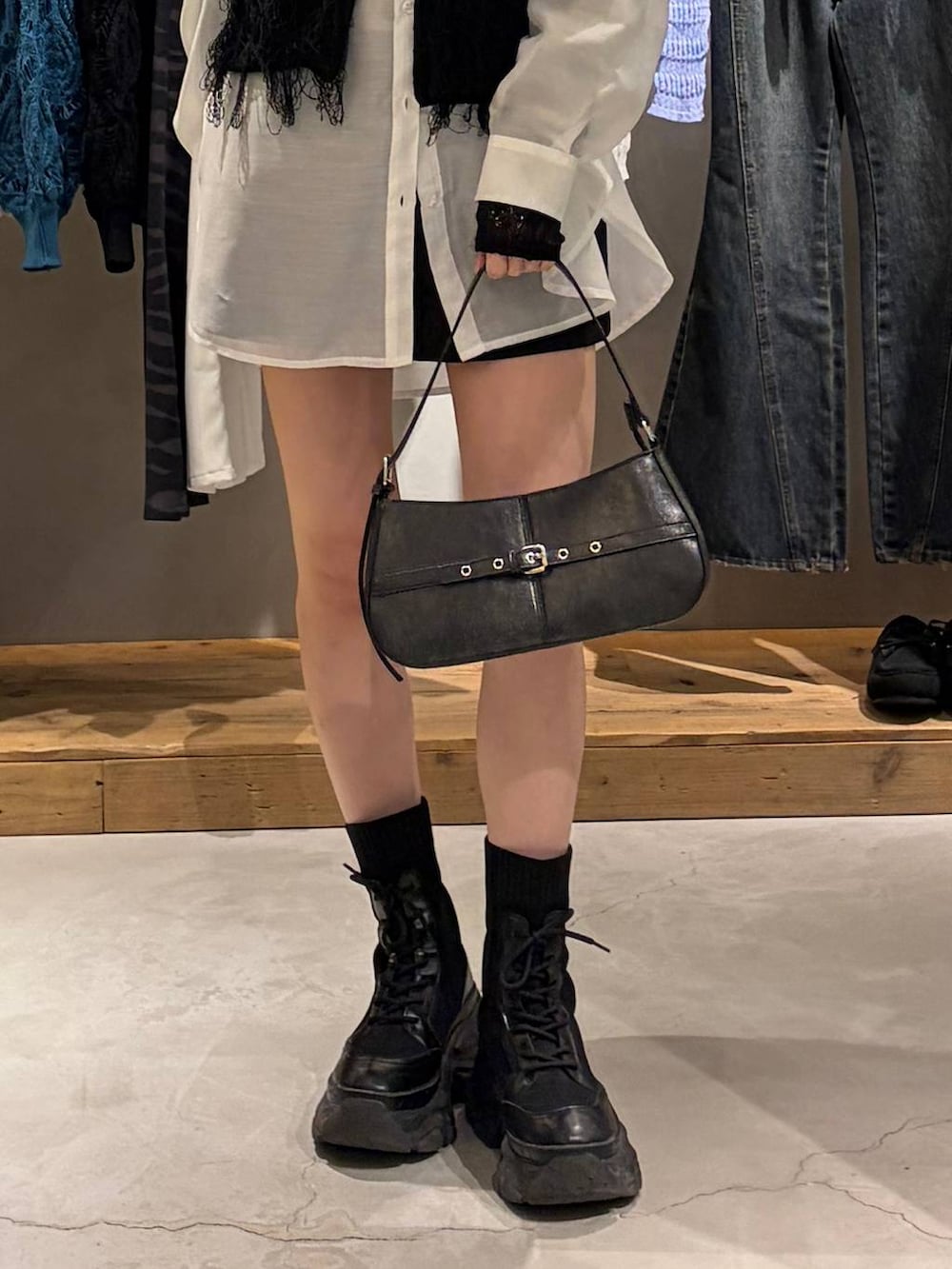 ブラック系のブーツ、ブラック系のハンドバッグ、ブラック系のベストを着用したレディースの春コーディネートの5枚目の写真