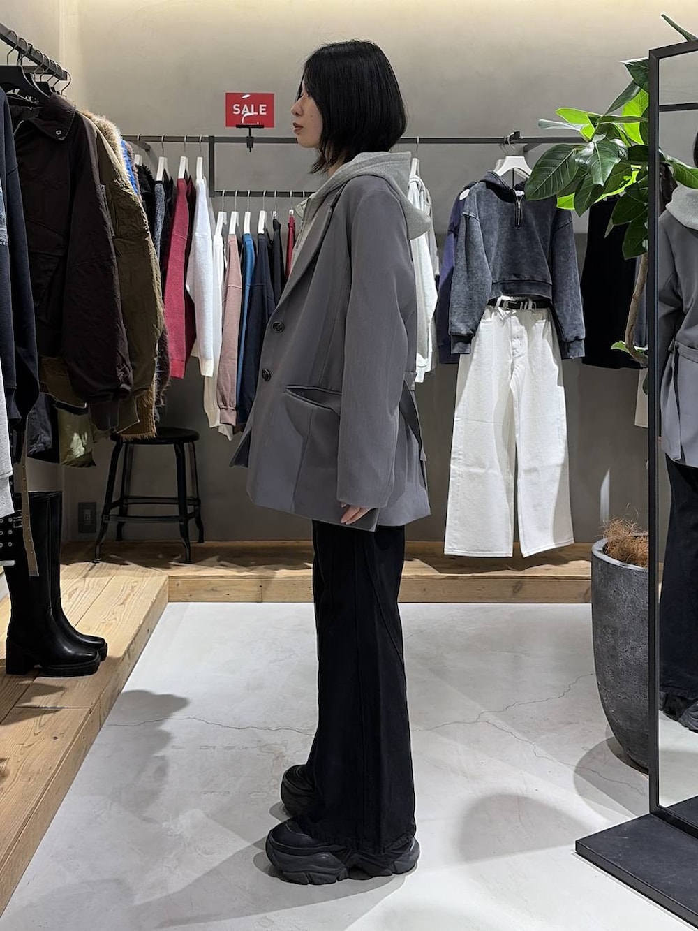 ブラック系のブーツ、ブラック系のデニムパンツ、グレー系のパーカーを着用したレディースの冬コーディネートの2枚目の写真