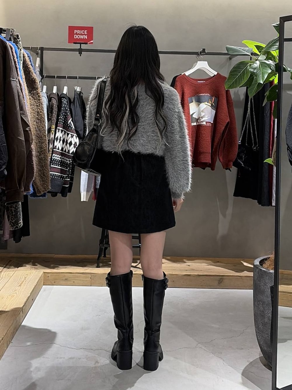 ブラック系のブーツ、ブラック系のスカート、ブラック系のショルダーバッグを着用したレディースの冬コーディネートの3枚目の写真