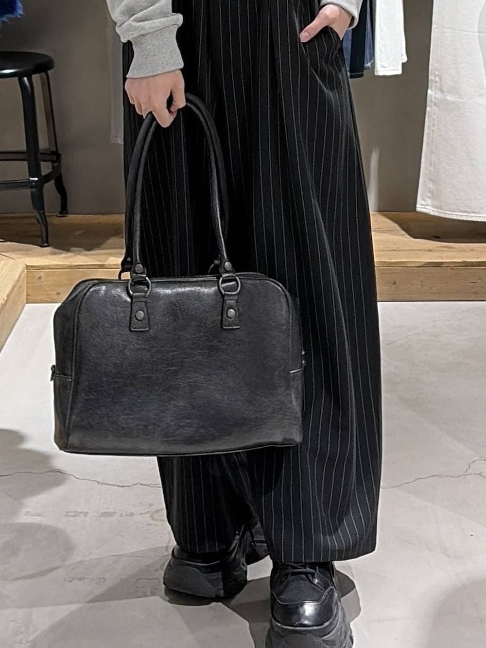 ブラック系のブーツ、ブラック系のボストンバッグ、グレー系のパーカーを着用したレディースの冬コーディネートの6枚目の写真