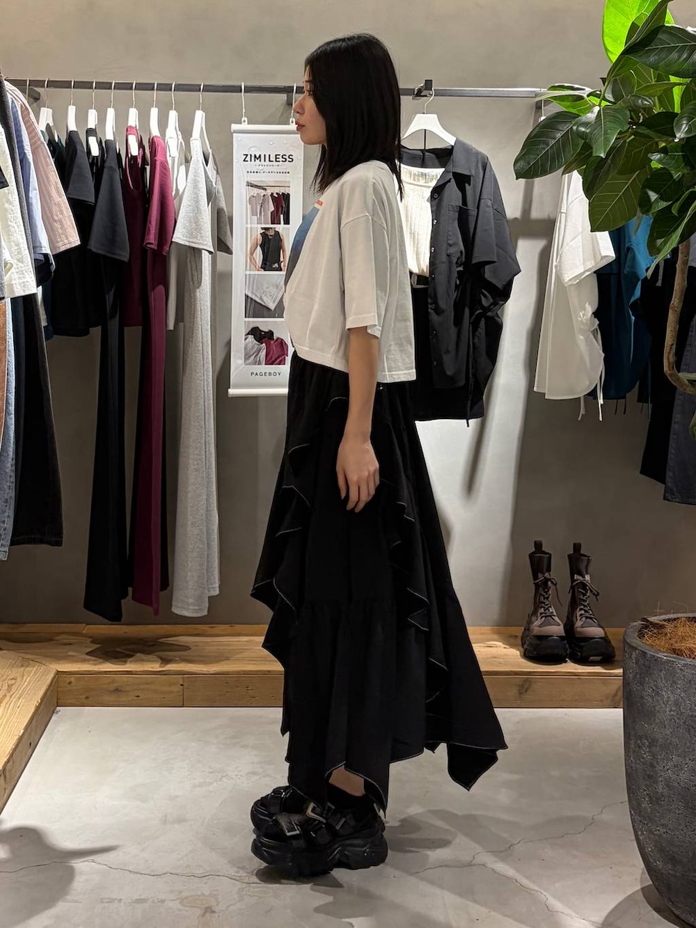 ブラック系のスカート、ブラック系のサンダル、ホワイト系のTシャツ/カットソーを着用したレディースの春コーディネートの2枚目の写真