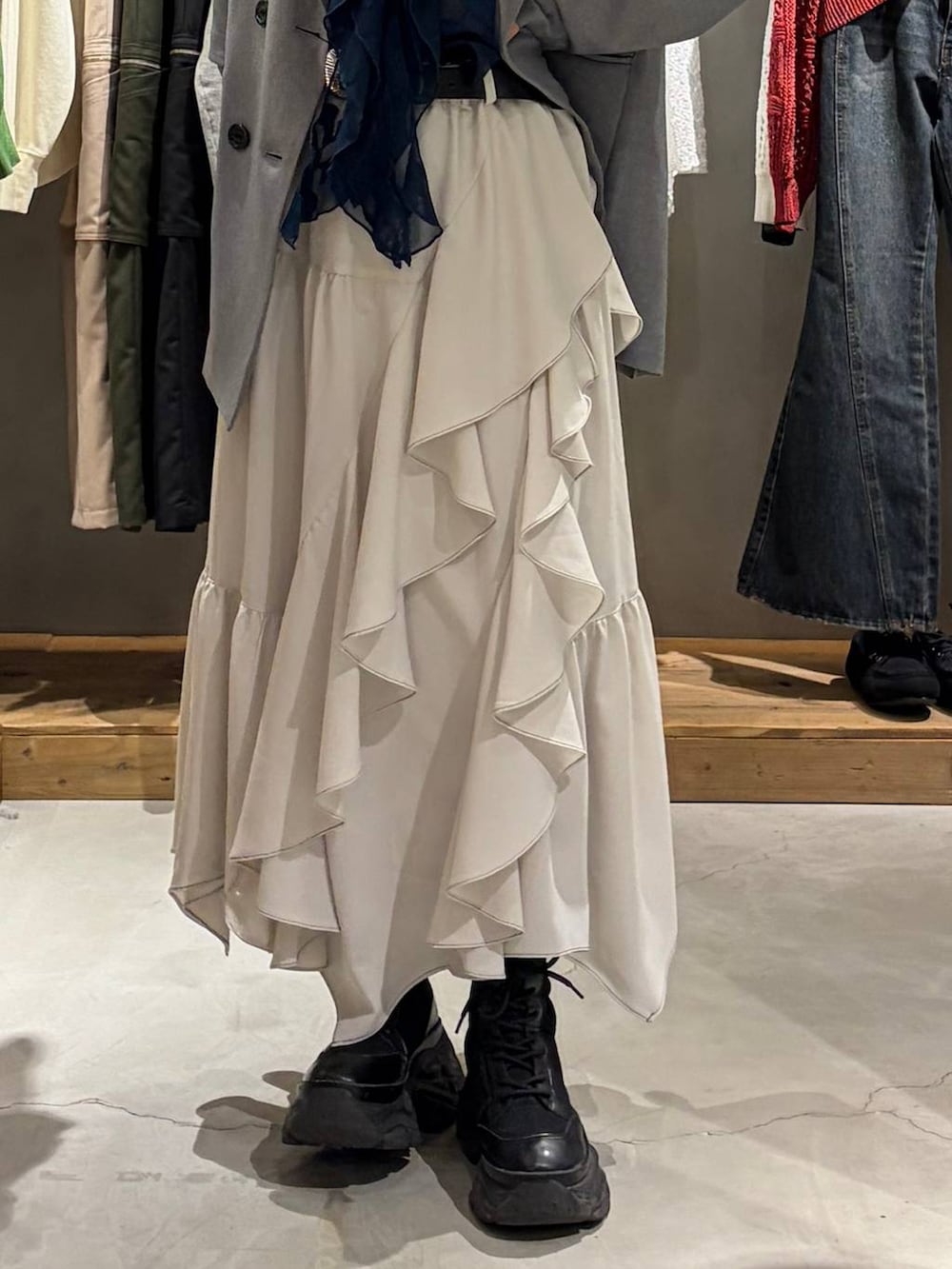 ブラック系のブーツ、ベージュ系のスカート、グレー系のテーラードジャケットを着用したレディースの春コーディネートの5枚目の写真