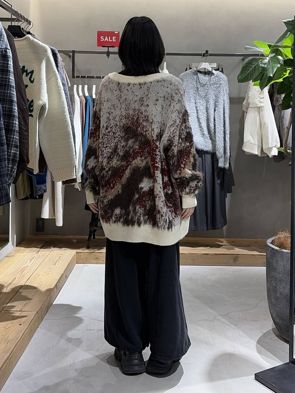 ブラック系のブーツ、ホワイト系のカーディガン/ボレロ、ブラック系のニット/セーターを着用したレディースの冬コーディネートの3枚目の写真