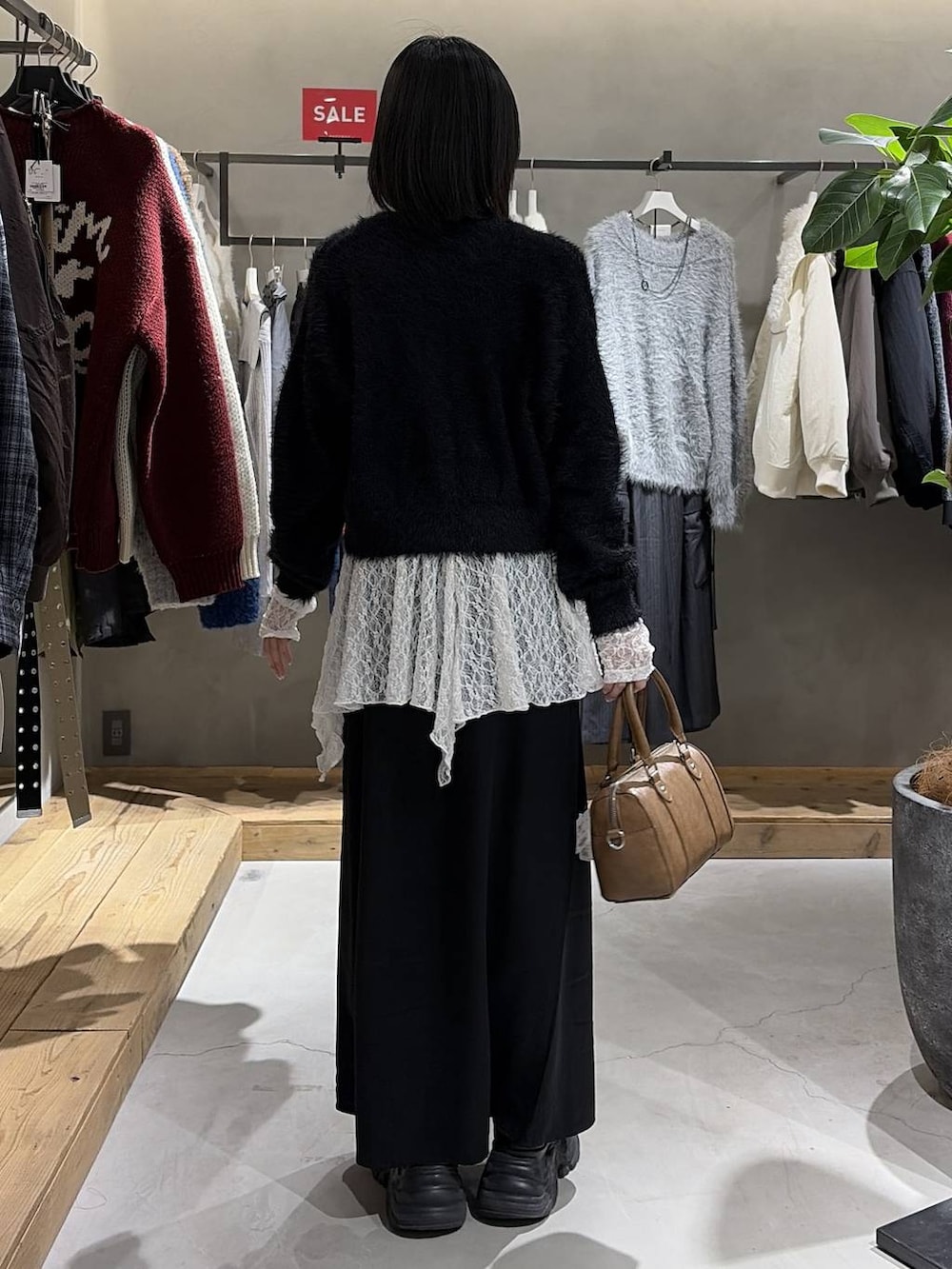 ブラック系のスカート、ブラウン系のボストンバッグ、ホワイト系のチュニックを着用したレディースの冬コーディネートの3枚目の写真