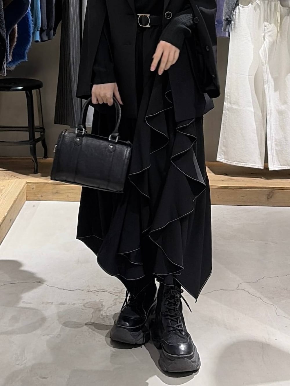 ブラック系のブーツ、ブラック系のスカート、ブラック系のボストンバッグを着用したレディースの冬コーディネートの5枚目の写真