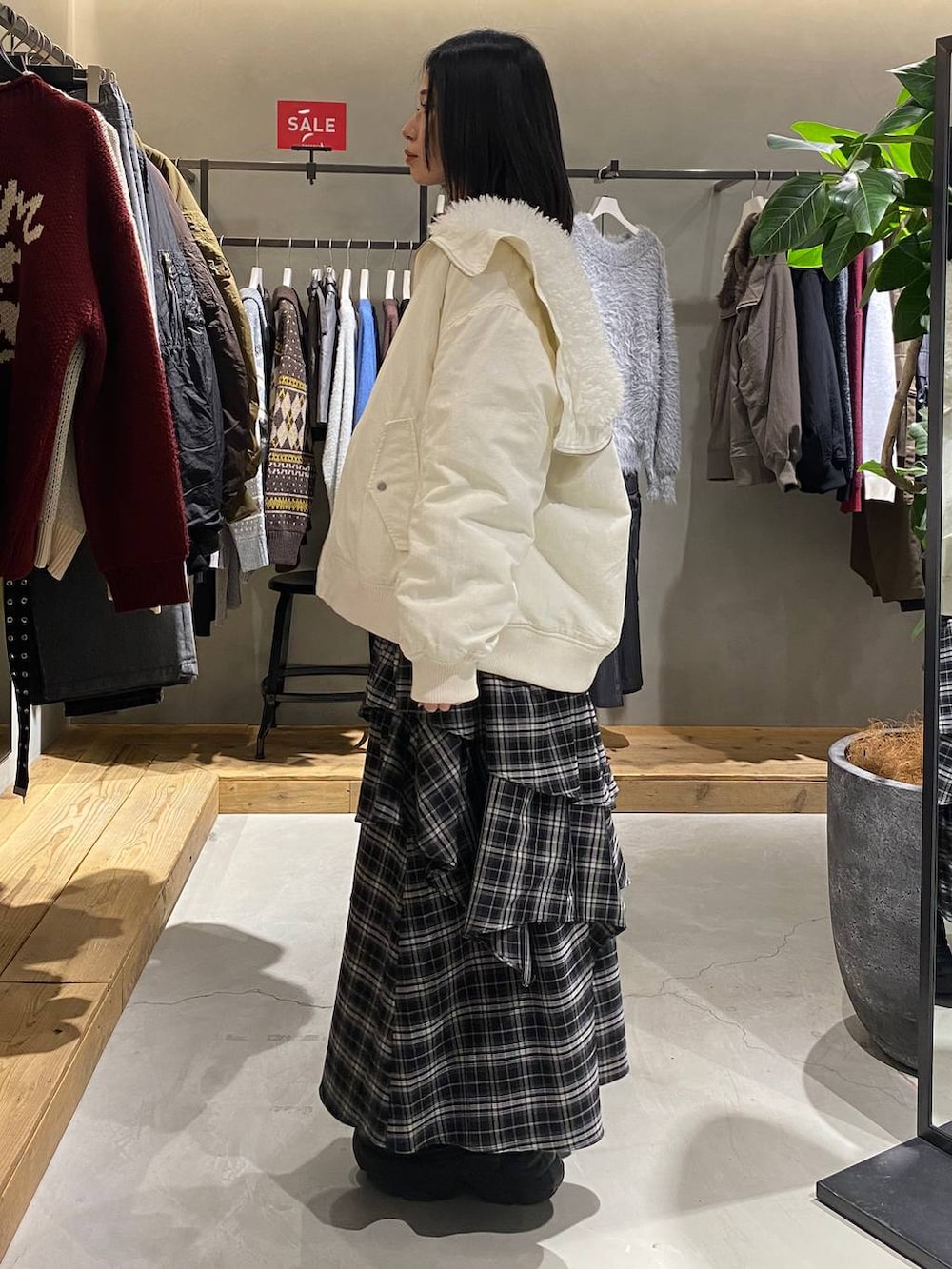 ブラック系のブーツ、ホワイト系のブルゾン、ホワイト系のスカートを着用したレディースの冬コーディネートの2枚目の写真