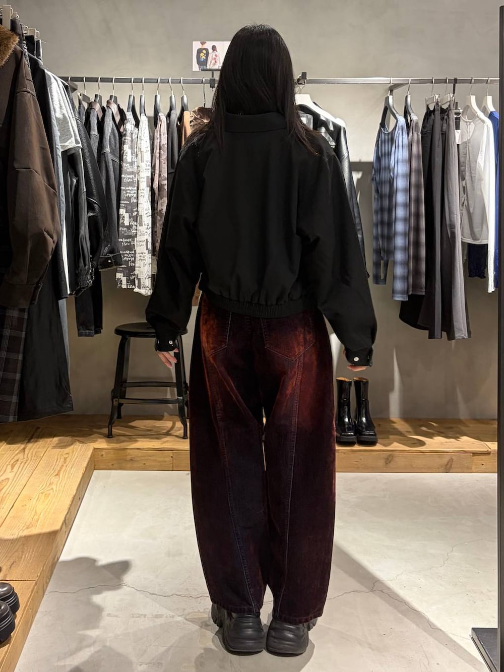 グレー系のスウェット、ブラック系のブルゾン、レッド系のデニムパンツを着用したレディースの秋コーディネートの3枚目の写真