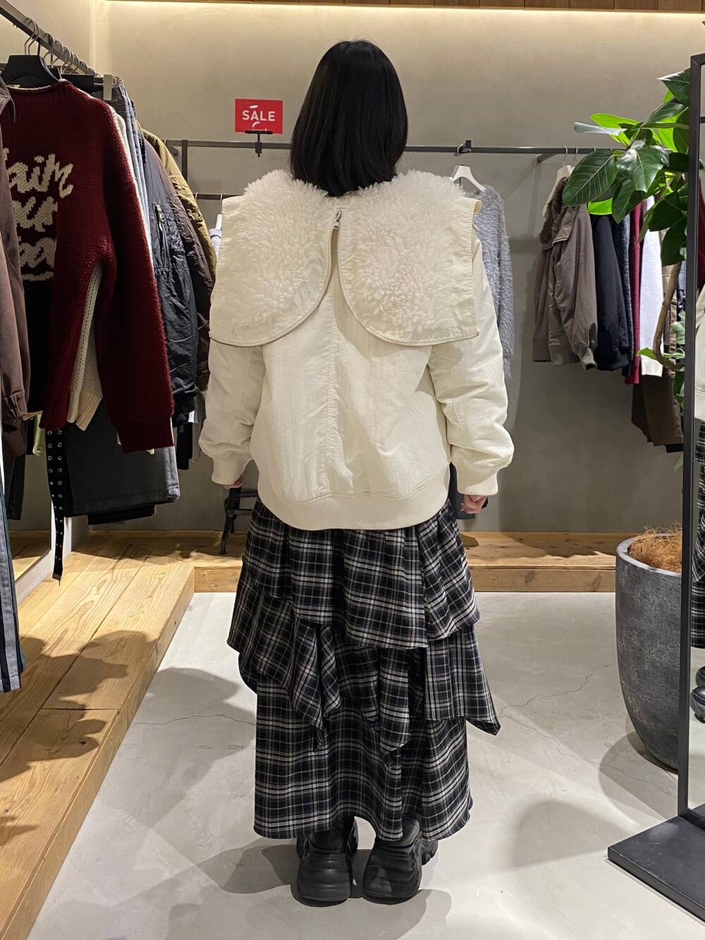 ブラック系のブーツ、ホワイト系のブルゾン、ホワイト系のスカートを着用したレディースの冬コーディネートの3枚目の写真