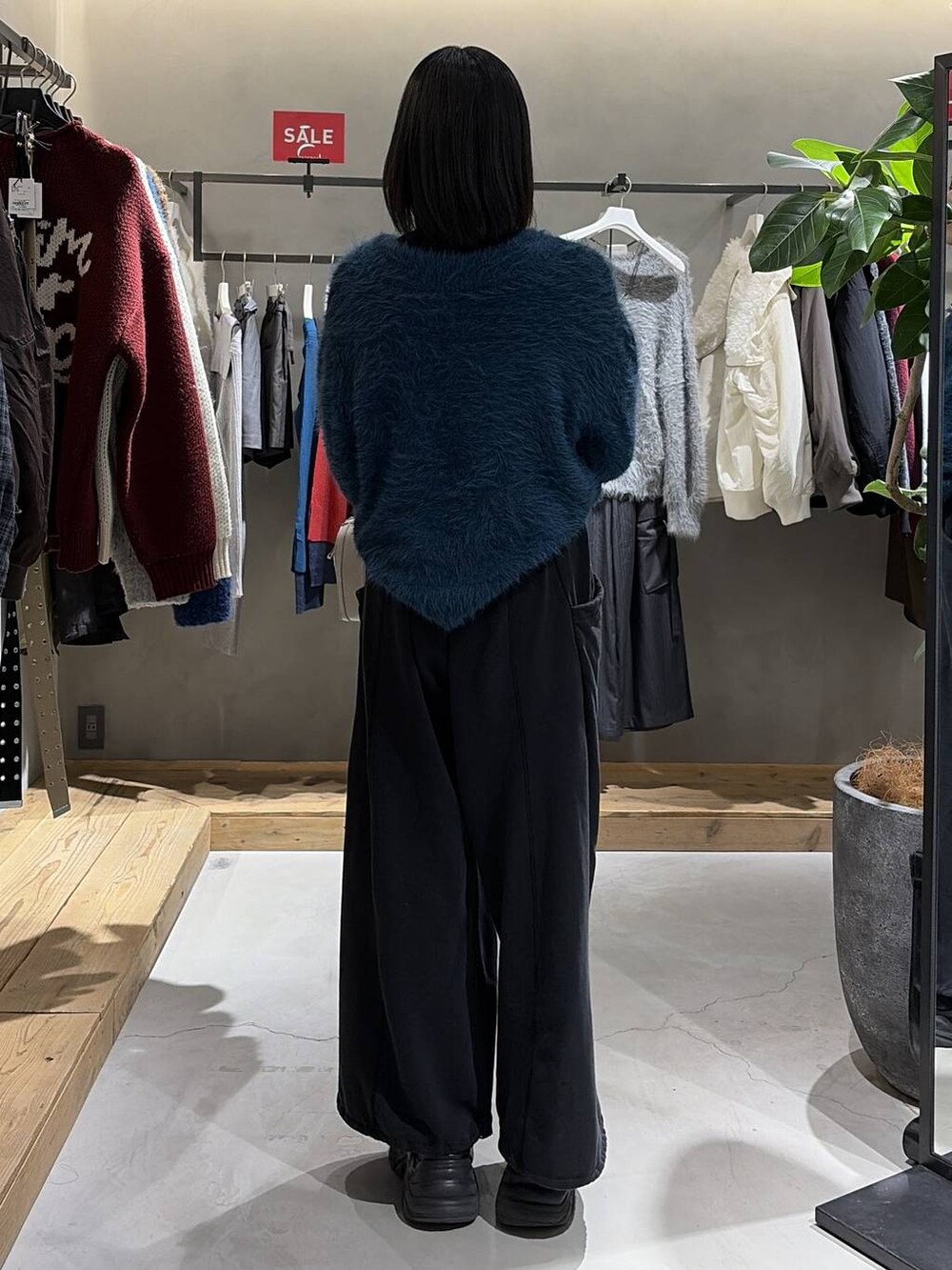 ブラック系のブーツ、ブルー系のニット/セーター、ホワイト系のボストンバッグを着用したレディースの冬コーディネートの3枚目の写真