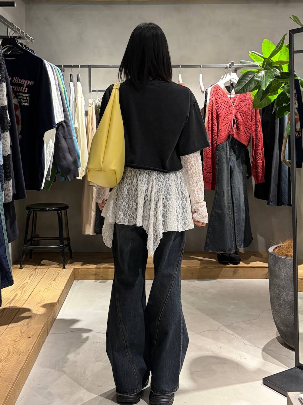 ブルー系のデニムパンツ、イエロー系のトートバッグ、ホワイト系のチュニックを着用したレディースの春コーディネートの3枚目の写真