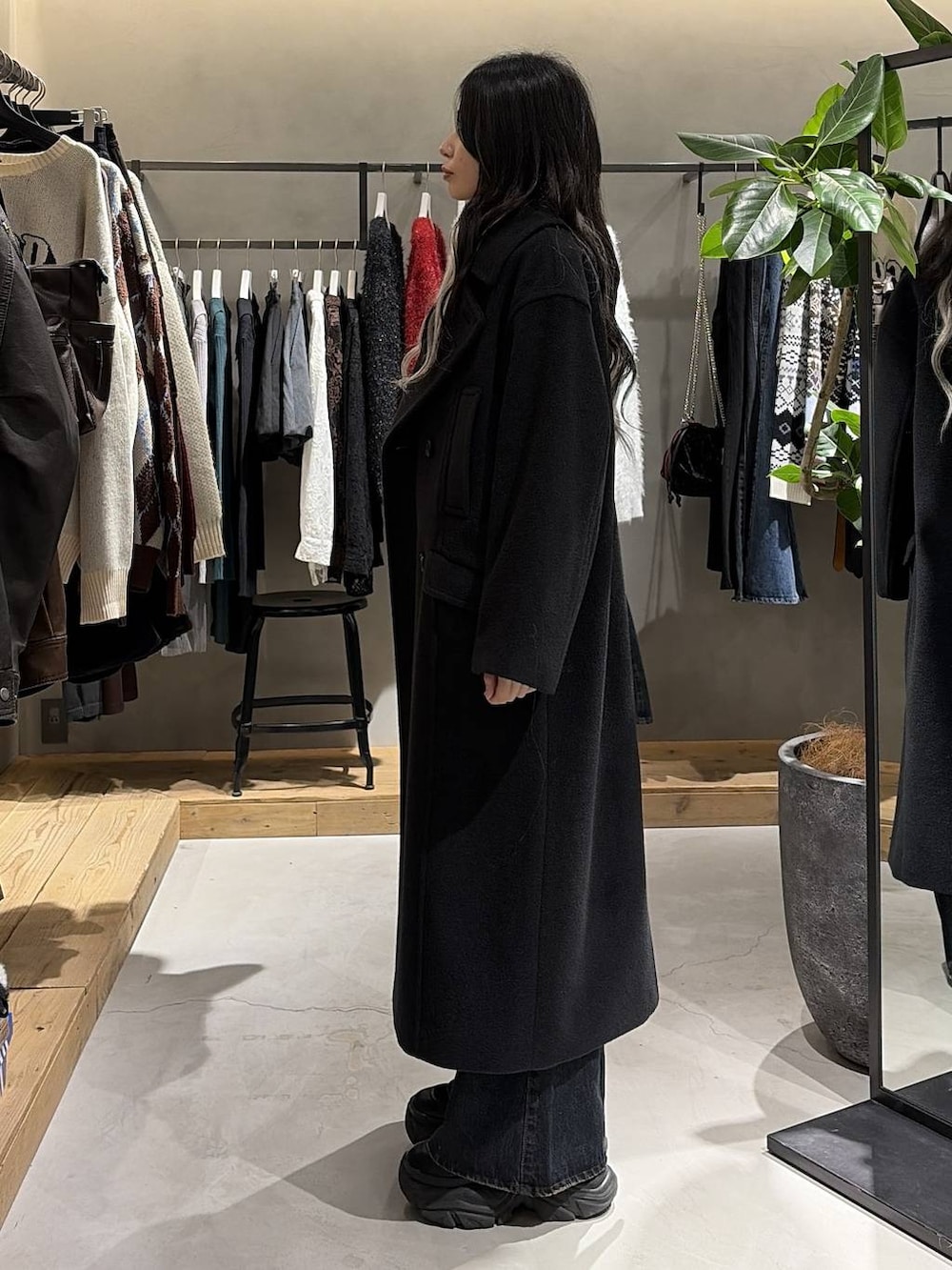 ブラック系のブーツ、ブルー系のデニムパンツ、ブラック系のチェスターコートを着用したレディースの冬コーディネートの2枚目の写真