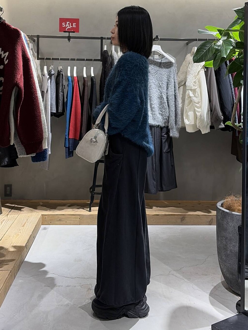 ブラック系のブーツ、ブルー系のニット/セーター、ホワイト系のボストンバッグを着用したレディースの冬コーディネートの2枚目の写真