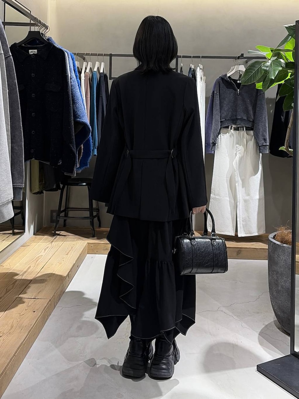 ブラック系のブーツ、ブラック系のスカート、ブラック系のボストンバッグを着用したレディースの冬コーディネートの3枚目の写真