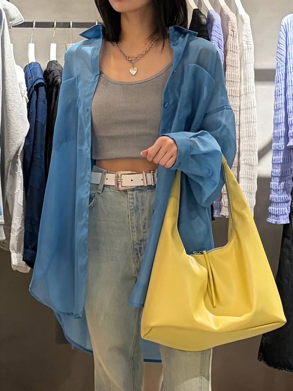 ブラック系のブーツ、グレー系のキャミソール、ブルー系のデニムパンツを着用したレディースの春コーディネートの4枚目の写真