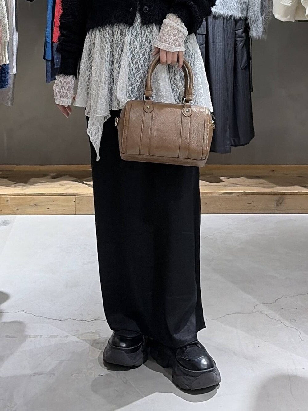 ブラック系のスカート、ブラウン系のボストンバッグ、ホワイト系のチュニックを着用したレディースの冬コーディネートの5枚目の写真