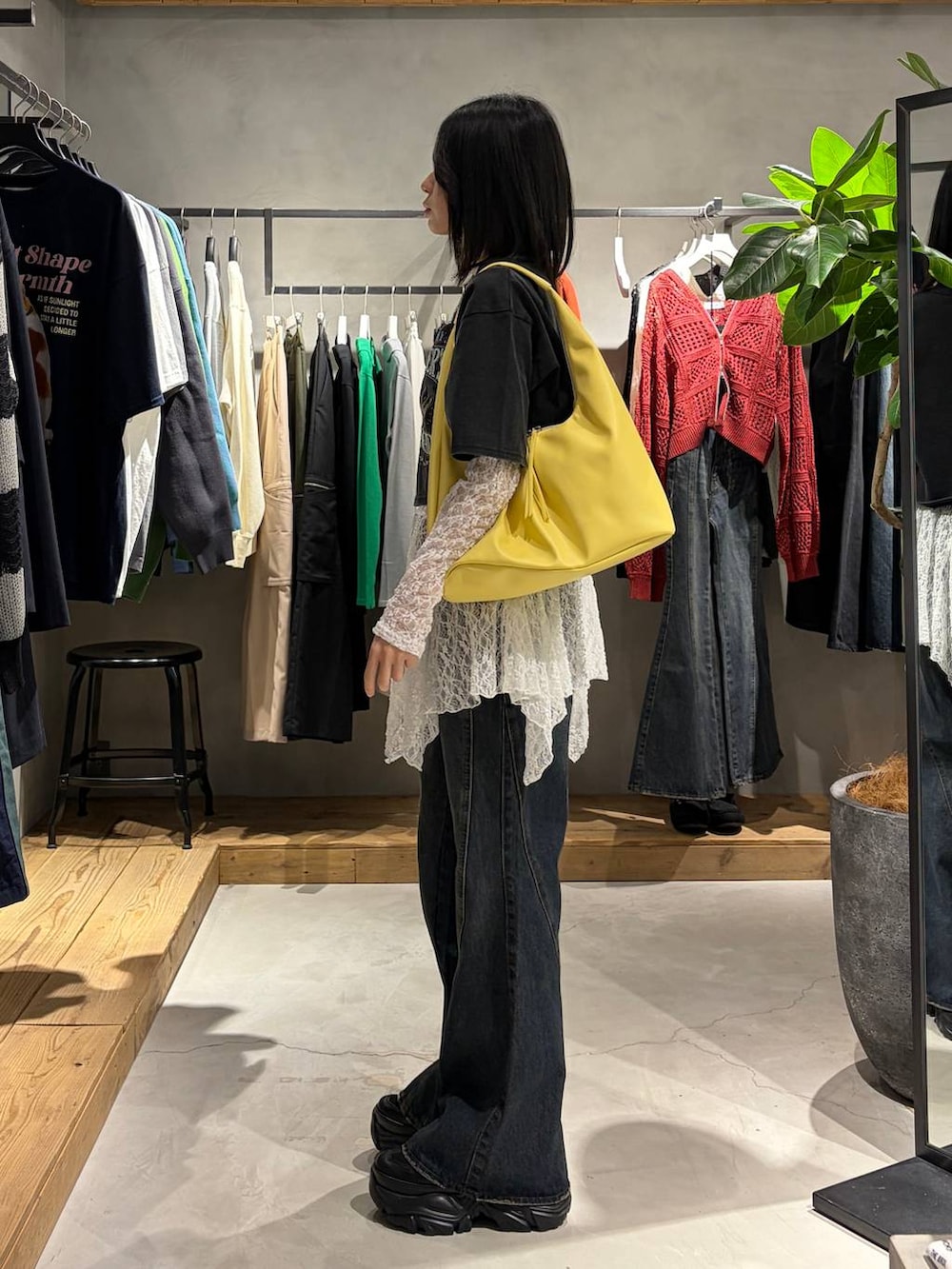 ブルー系のデニムパンツ、イエロー系のトートバッグ、ホワイト系のチュニックを着用したレディースの春コーディネートの2枚目の写真