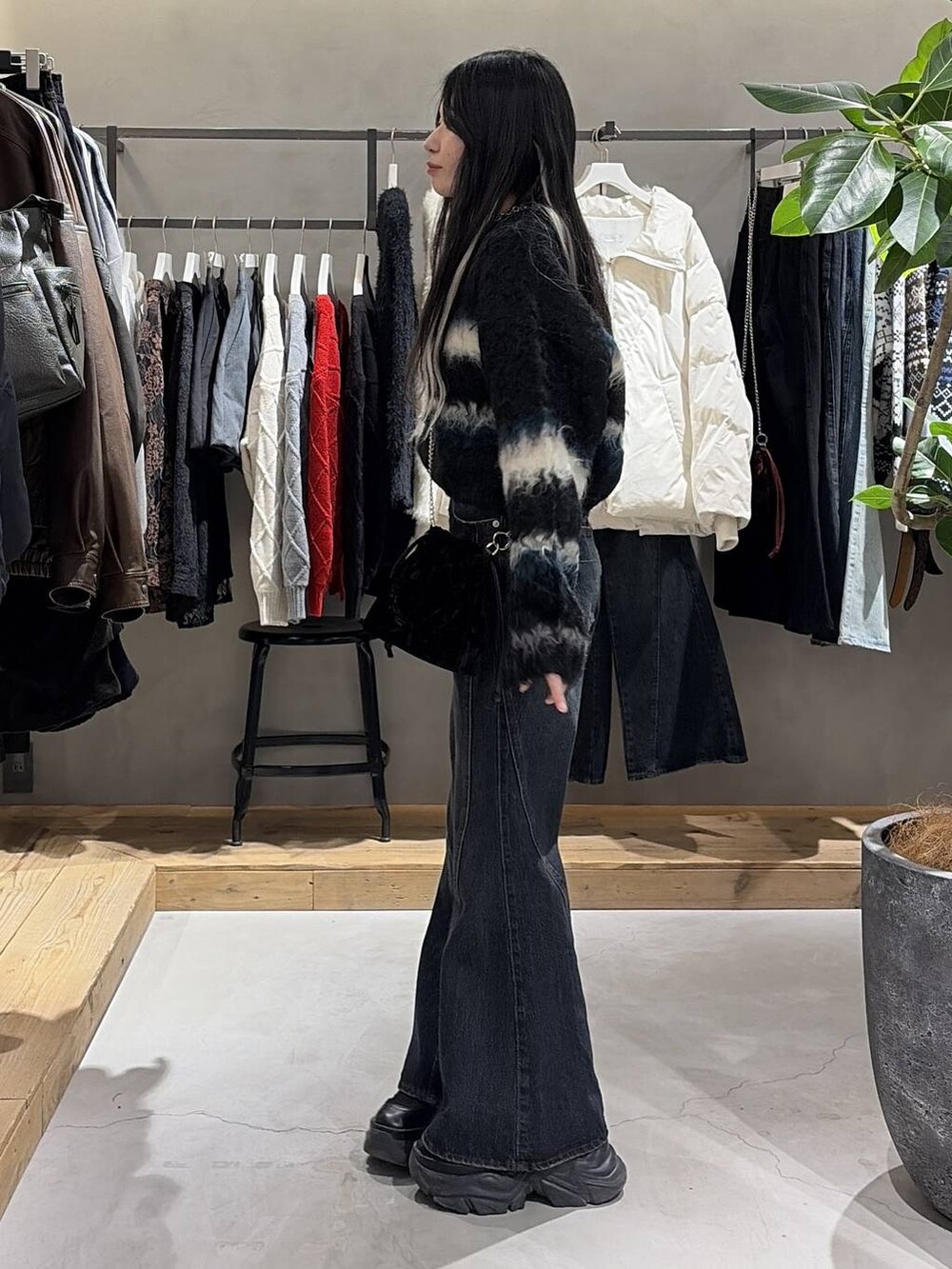 ブラック系のブーツ、ブルー系のデニムパンツ、ブラック系のハンドバッグを着用したレディースの冬コーディネートの2枚目の写真