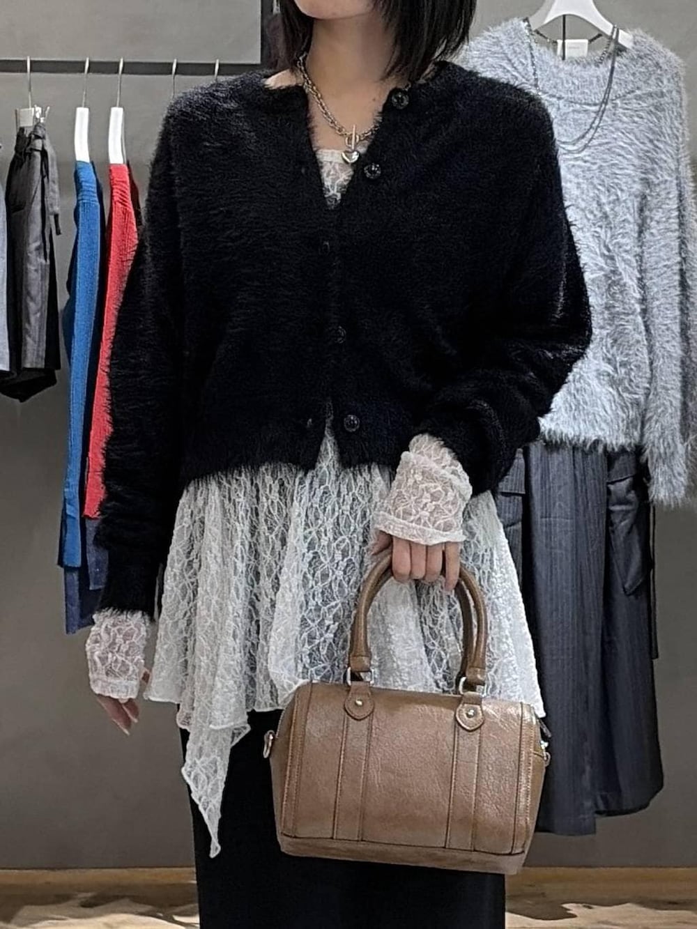 ブラック系のスカート、ブラウン系のボストンバッグ、ホワイト系のチュニックを着用したレディースの冬コーディネートの4枚目の写真