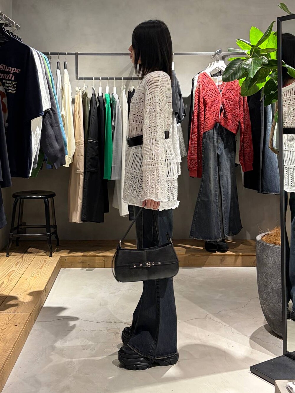 ブラック系のブーツ、ブルー系のデニムパンツ、ブラック系のハンドバッグを着用したレディースの春コーディネートの2枚目の写真