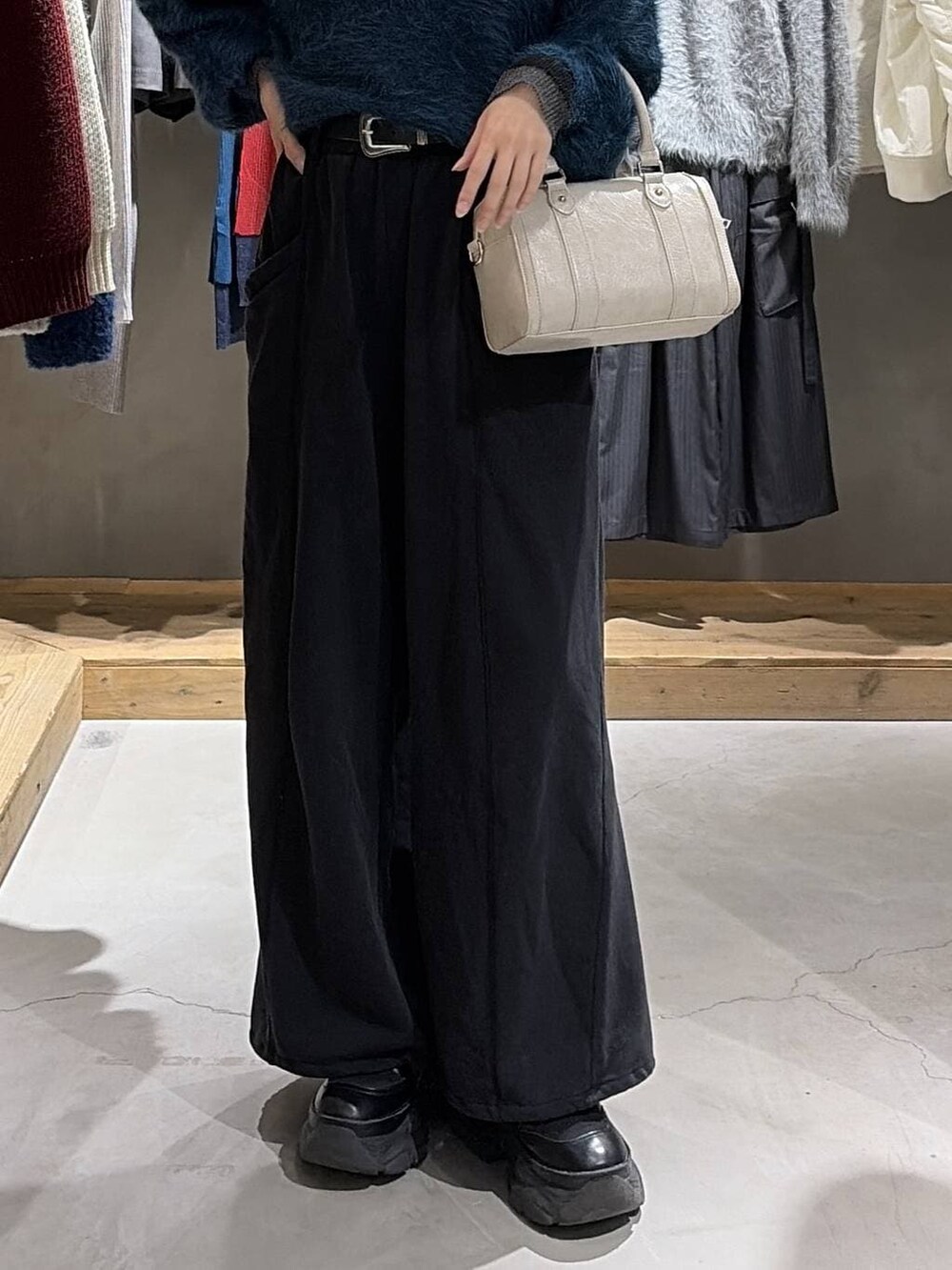 ブラック系のブーツ、ブルー系のニット/セーター、ホワイト系のボストンバッグを着用したレディースの冬コーディネートの5枚目の写真