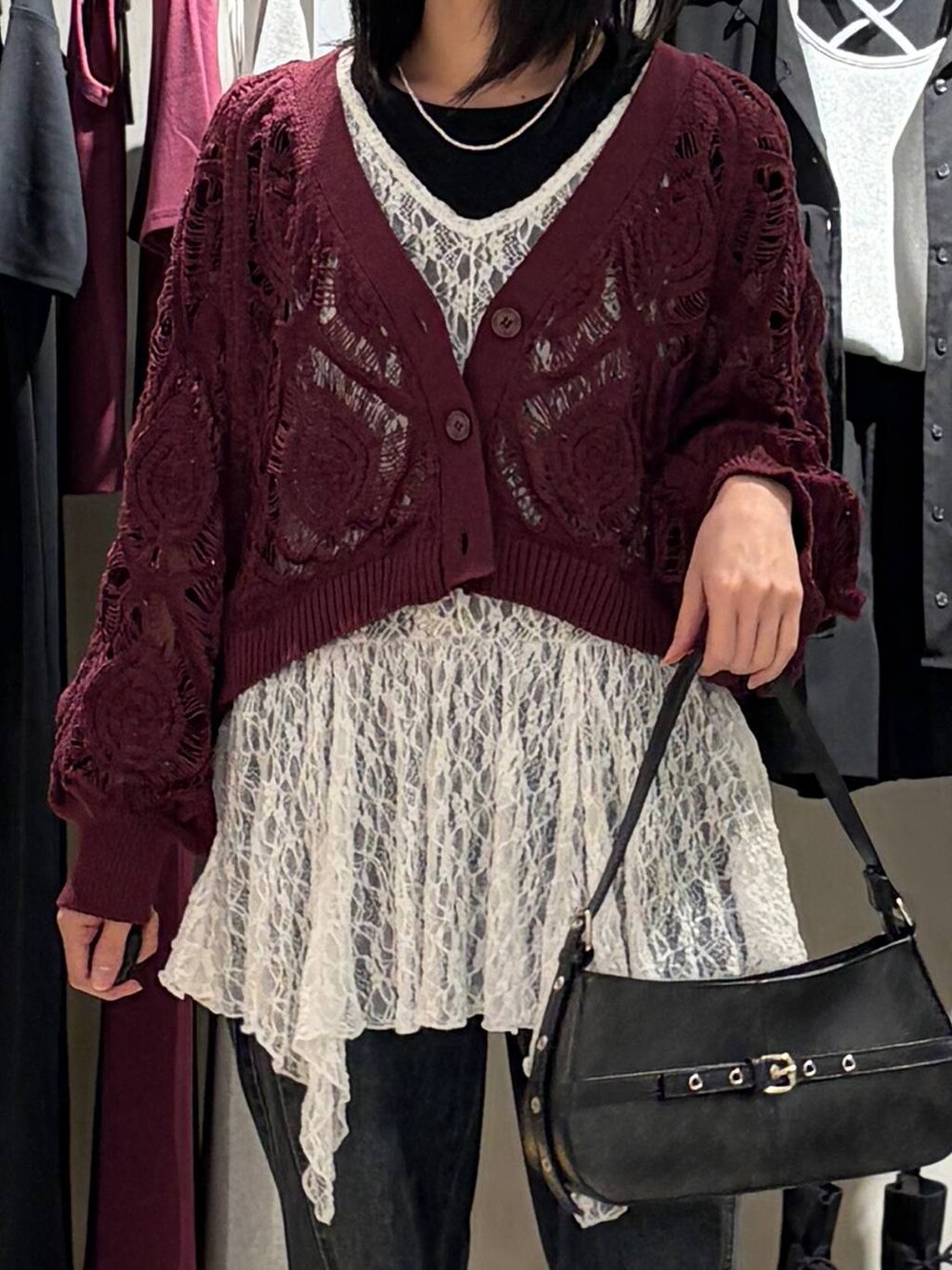 パープル系のカーディガン/ボレロ、ブルー系のデニムパンツ、ブラック系のハンドバッグを着用したレディースの春コーディネートの4枚目の写真