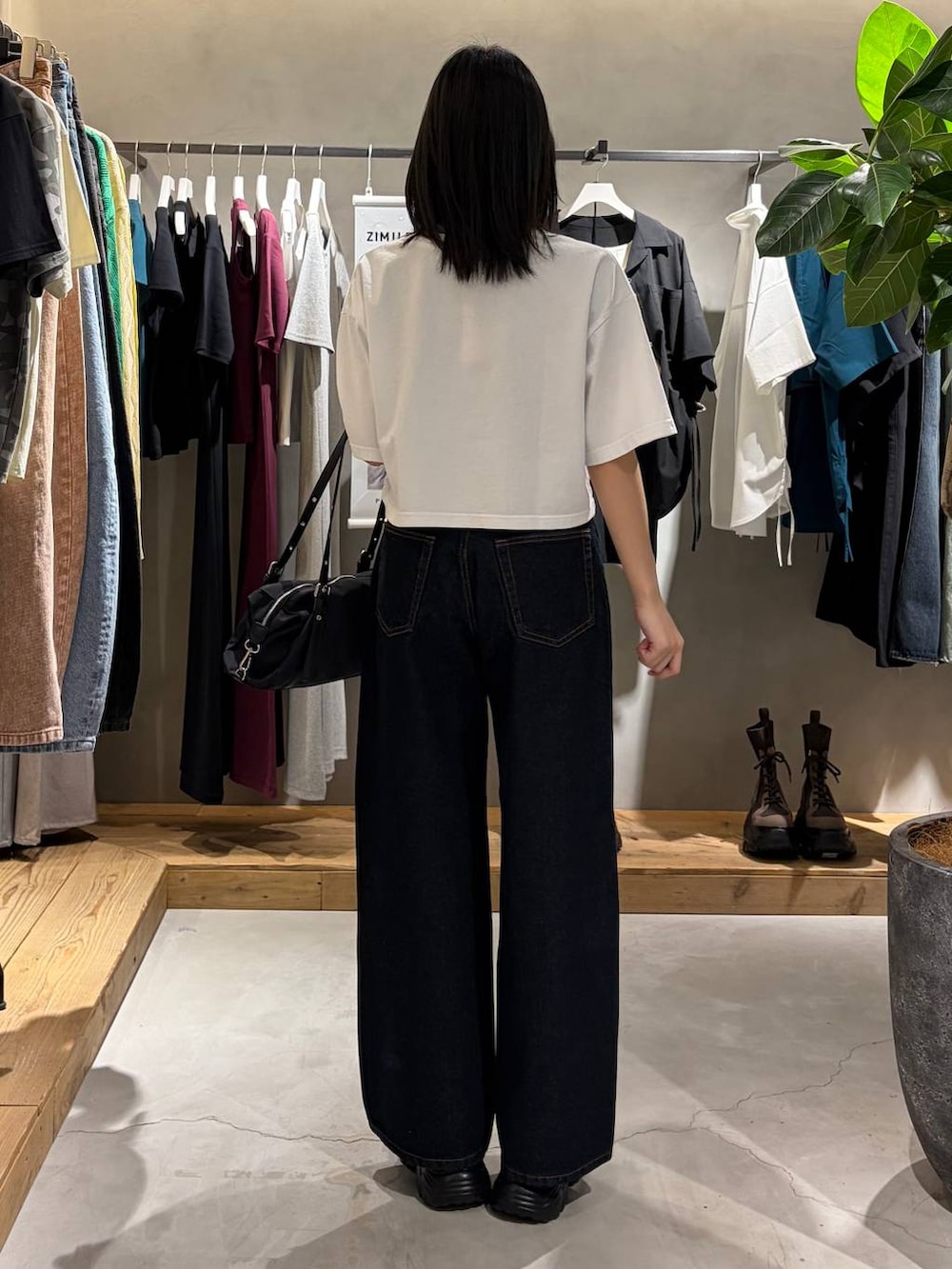 ブルー系のデニムパンツ、ブラック系のサンダル、ブラック系のトートバッグを着用したレディースの春コーディネートの3枚目の写真