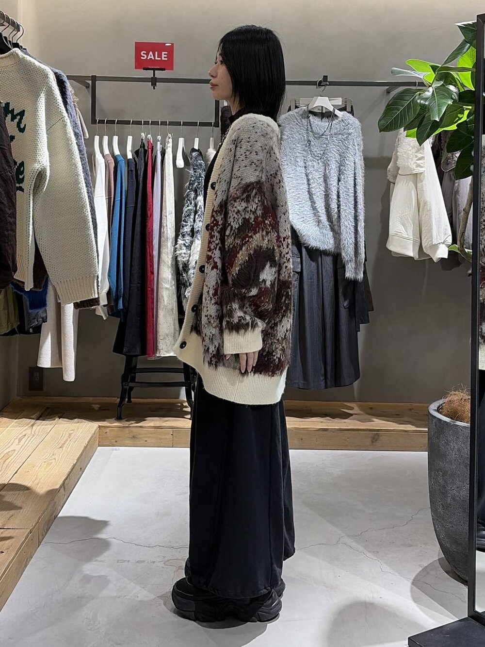 ブラック系のブーツ、ホワイト系のカーディガン/ボレロ、ブラック系のニット/セーターを着用したレディースの冬コーディネートの2枚目の写真