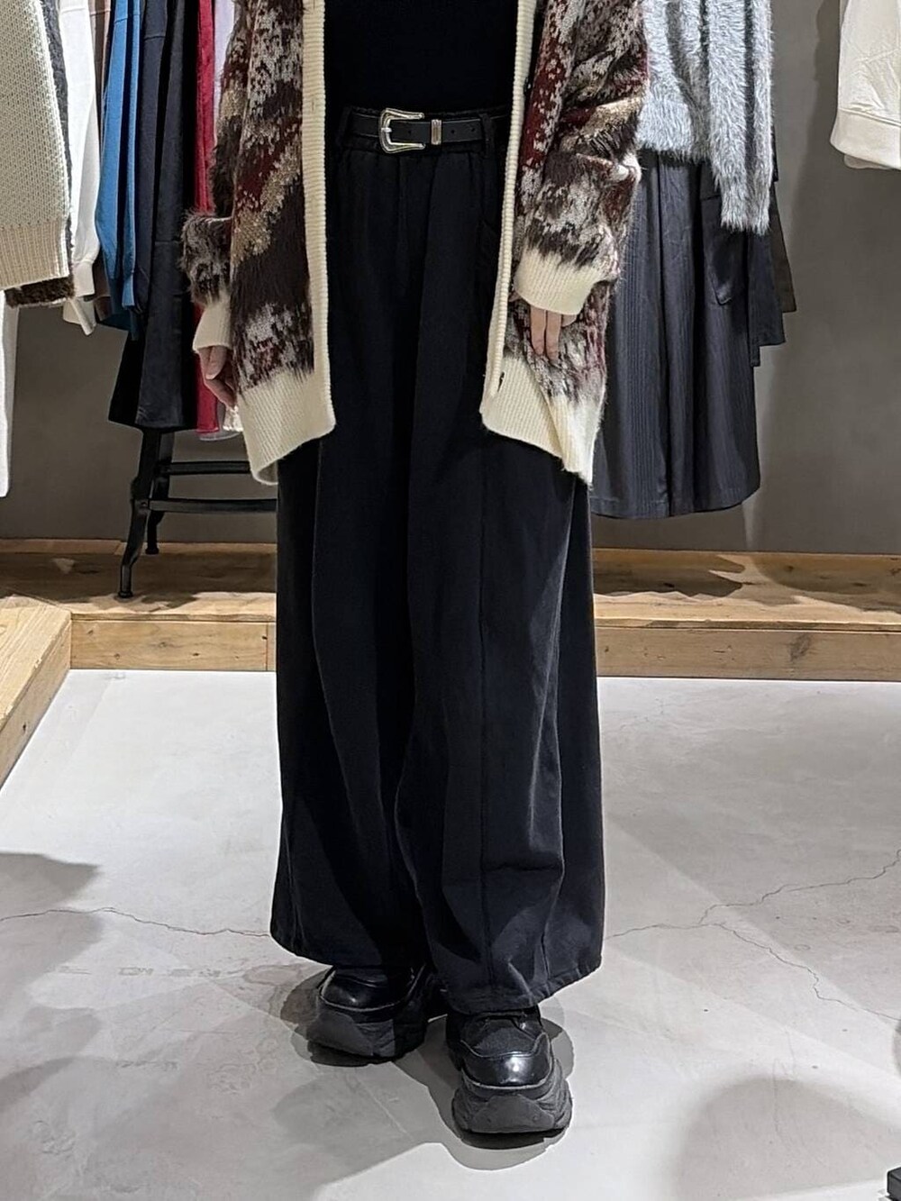 ブラック系のブーツ、ホワイト系のカーディガン/ボレロ、ブラック系のニット/セーターを着用したレディースの冬コーディネートの5枚目の写真