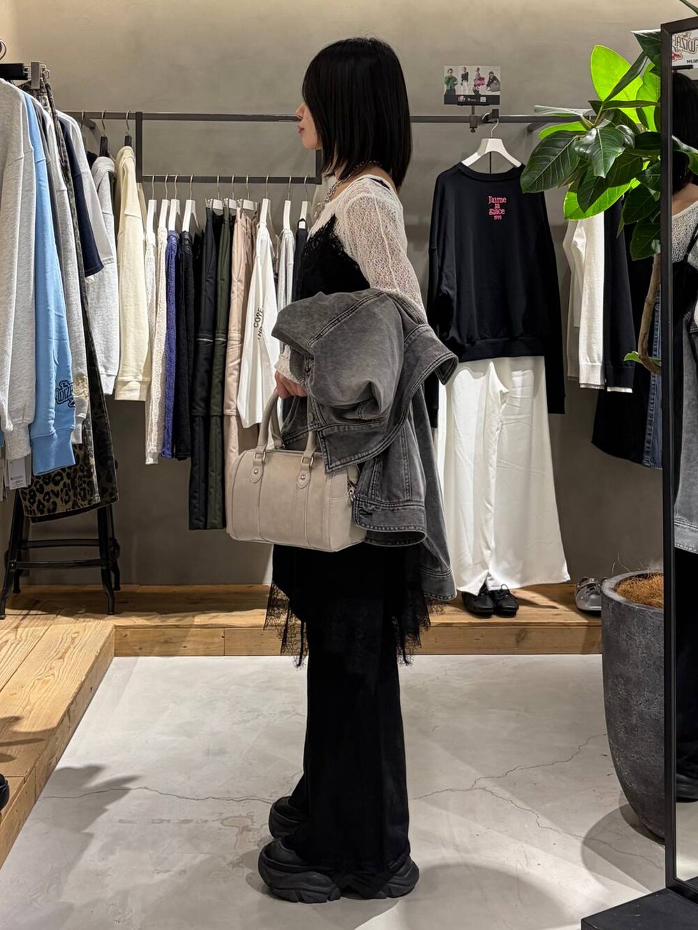 ブラック系のブーツ、ブラック系のデニムパンツ、ホワイト系のボストンバッグを着用したレディースの冬コーディネートの2枚目の写真