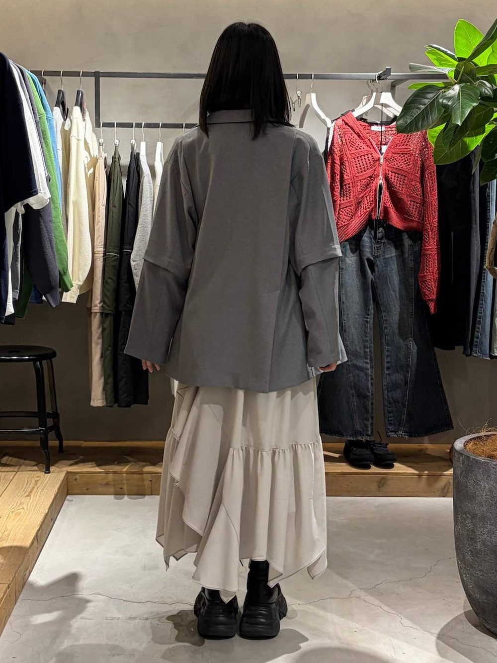 ブラック系のブーツ、ベージュ系のスカート、グレー系のテーラードジャケットを着用したレディースの春コーディネートの3枚目の写真