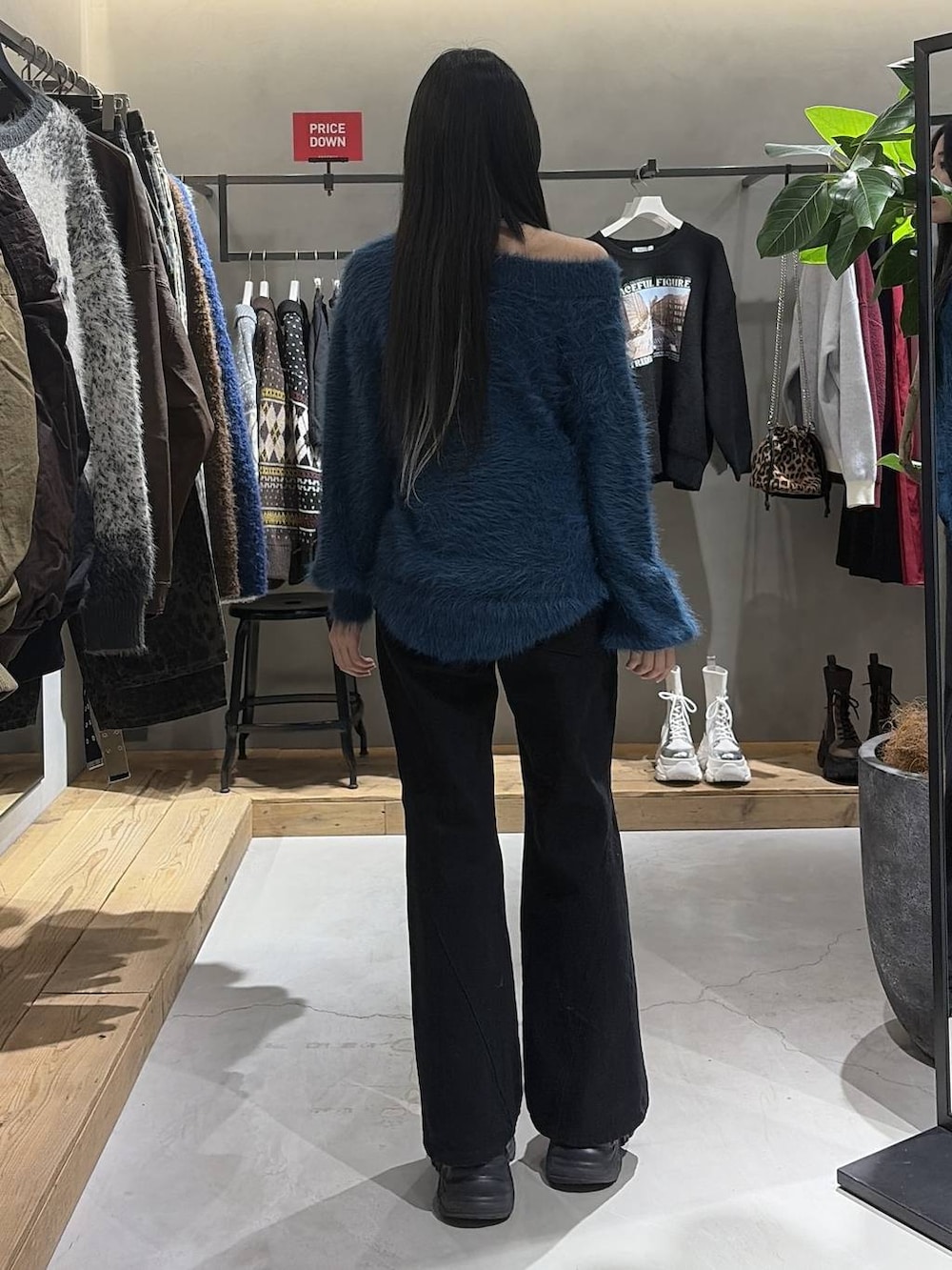 ブラック系のブーツ、ブラック系のデニムパンツ、ブルー系のニット/セーターを着用したレディースの冬コーディネートの3枚目の写真