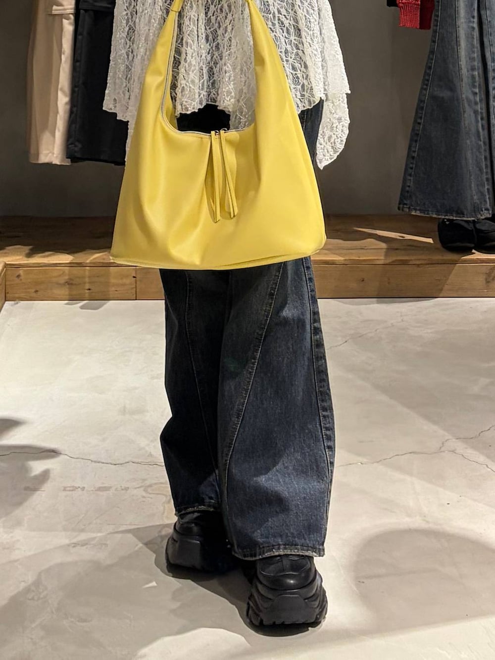 ブルー系のデニムパンツ、イエロー系のトートバッグ、ホワイト系のチュニックを着用したレディースの春コーディネートの5枚目の写真