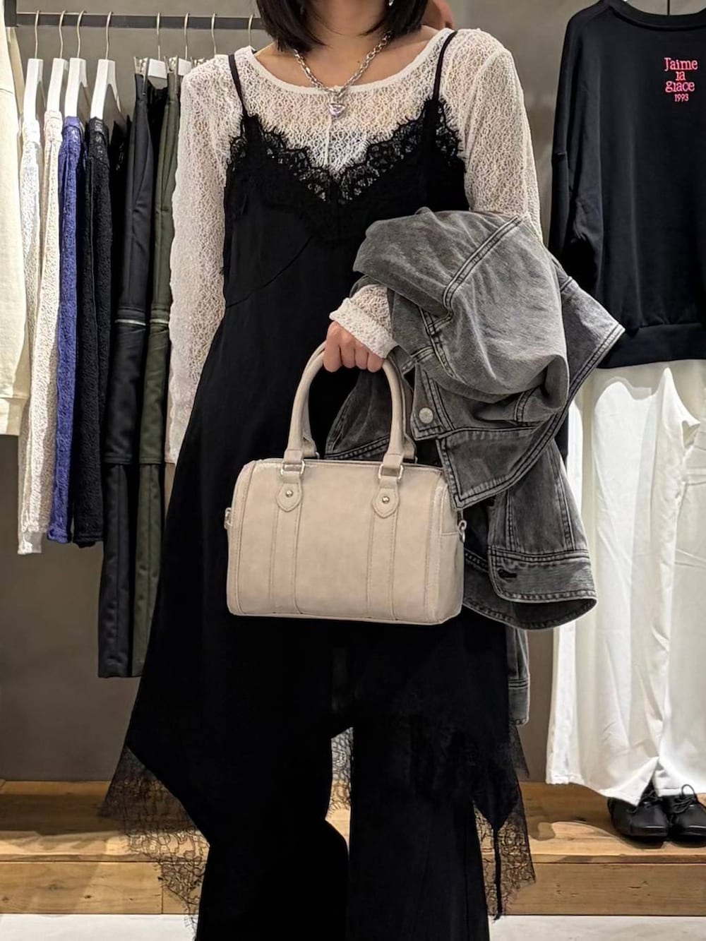 ブラック系のブーツ、ブラック系のデニムパンツ、ホワイト系のボストンバッグを着用したレディースの冬コーディネートの4枚目の写真