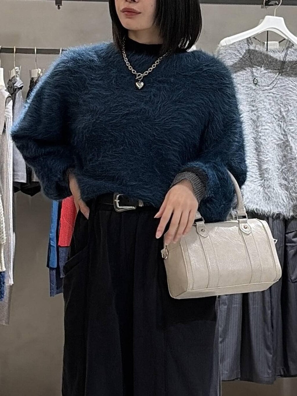 ブラック系のブーツ、ブルー系のニット/セーター、ホワイト系のボストンバッグを着用したレディースの冬コーディネートの4枚目の写真