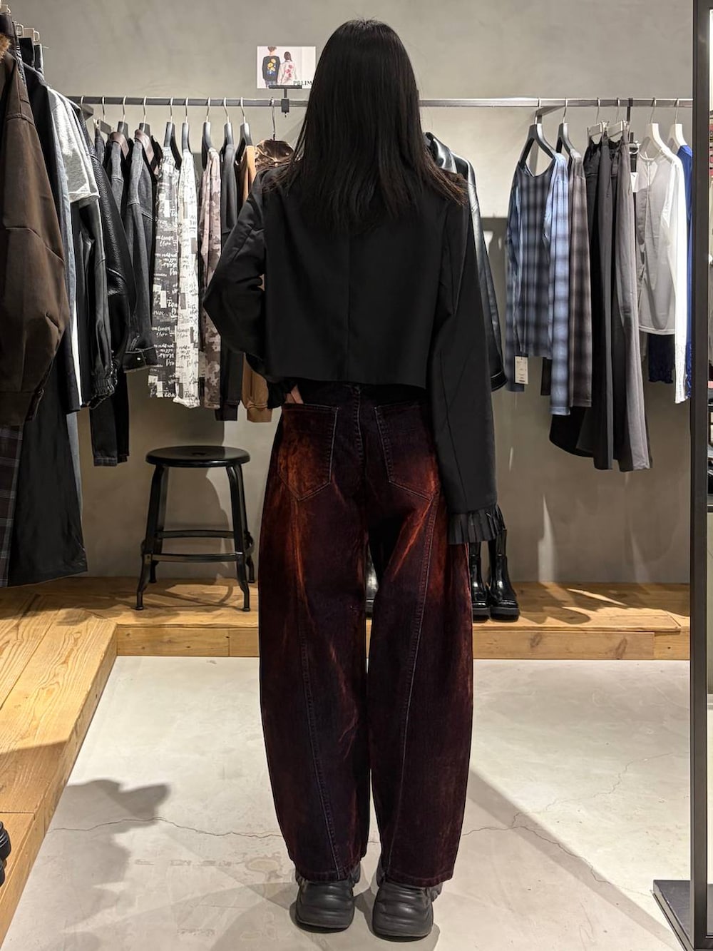 ブラック系のテーラードジャケット、レッド系のデニムパンツ、ブラック系のブーツを着用したレディースの秋コーディネートの3枚目の写真