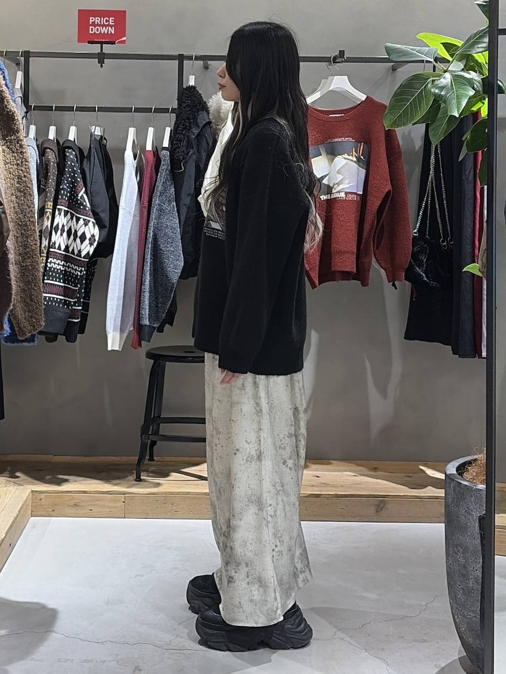 ブラック系のブーツ、ホワイト系のスカート、ブラック系のニット/セーターを着用したレディースの冬コーディネートの2枚目の写真