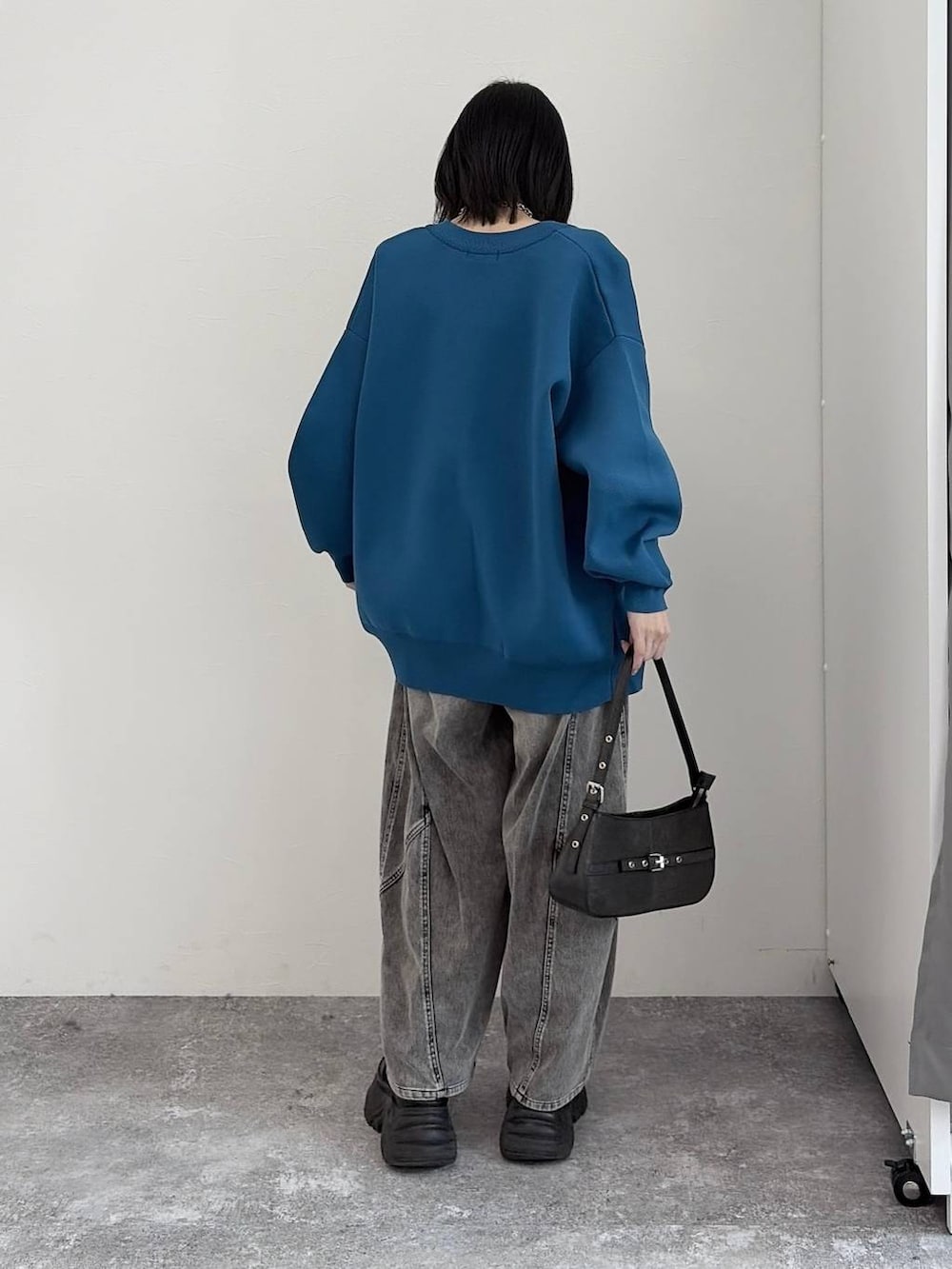 ブラック系のブーツ、ブラック系のハンドバッグ、ブルー系のカーディガン/ボレロを着用したレディースの冬コーディネートの3枚目の写真