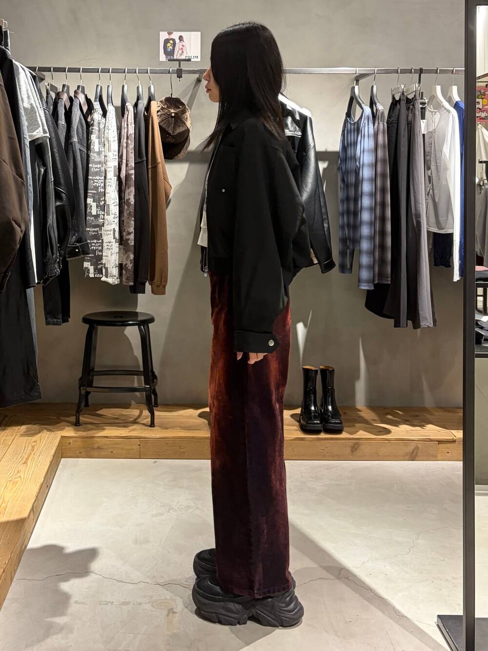 グレー系のスウェット、ブラック系のブルゾン、レッド系のデニムパンツを着用したレディースの秋コーディネートの2枚目の写真