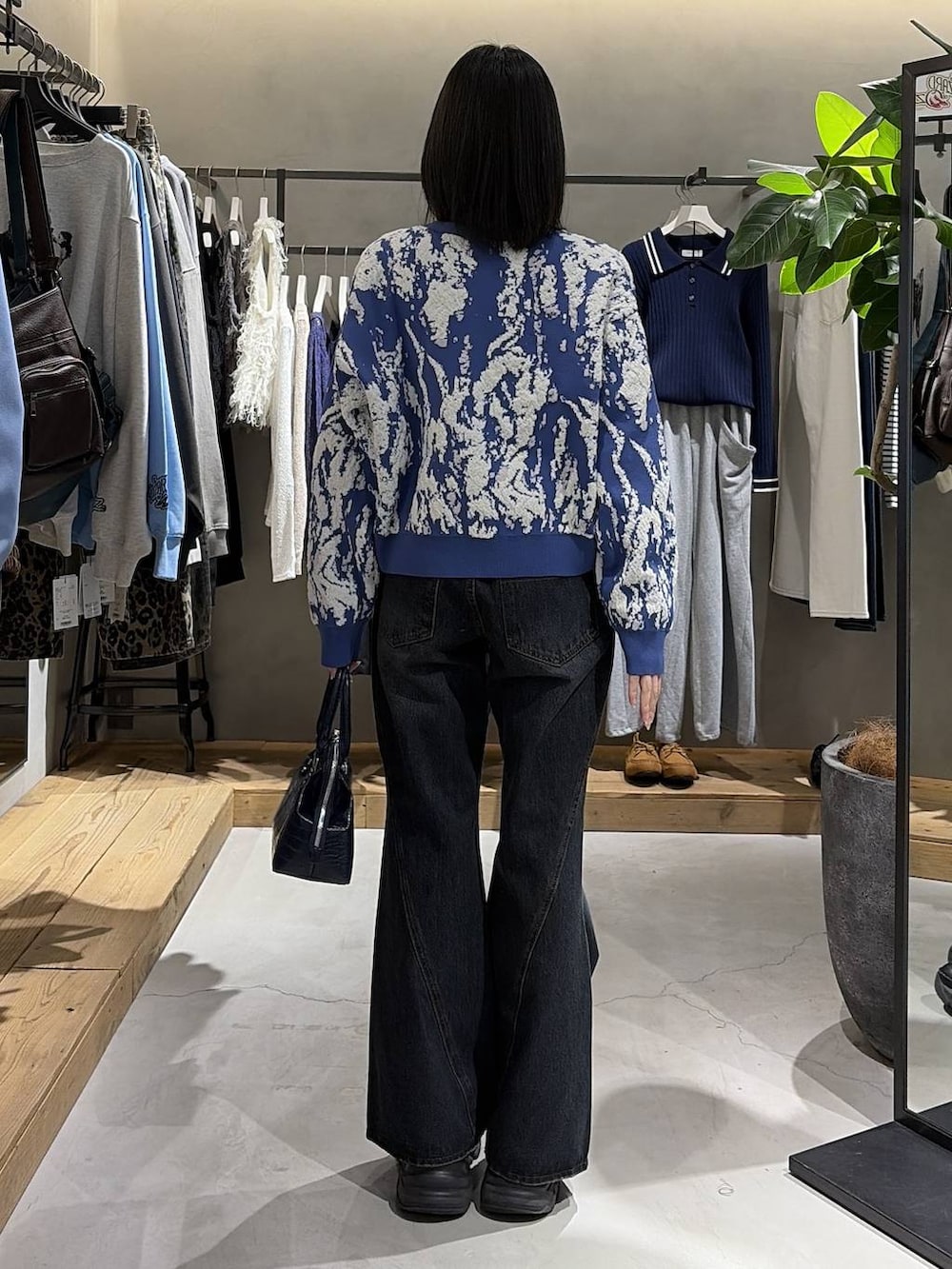 ブラック系のブーツ、ブルー系のデニムパンツ、ブルー系のハンドバッグを着用したレディースの冬コーディネートの3枚目の写真