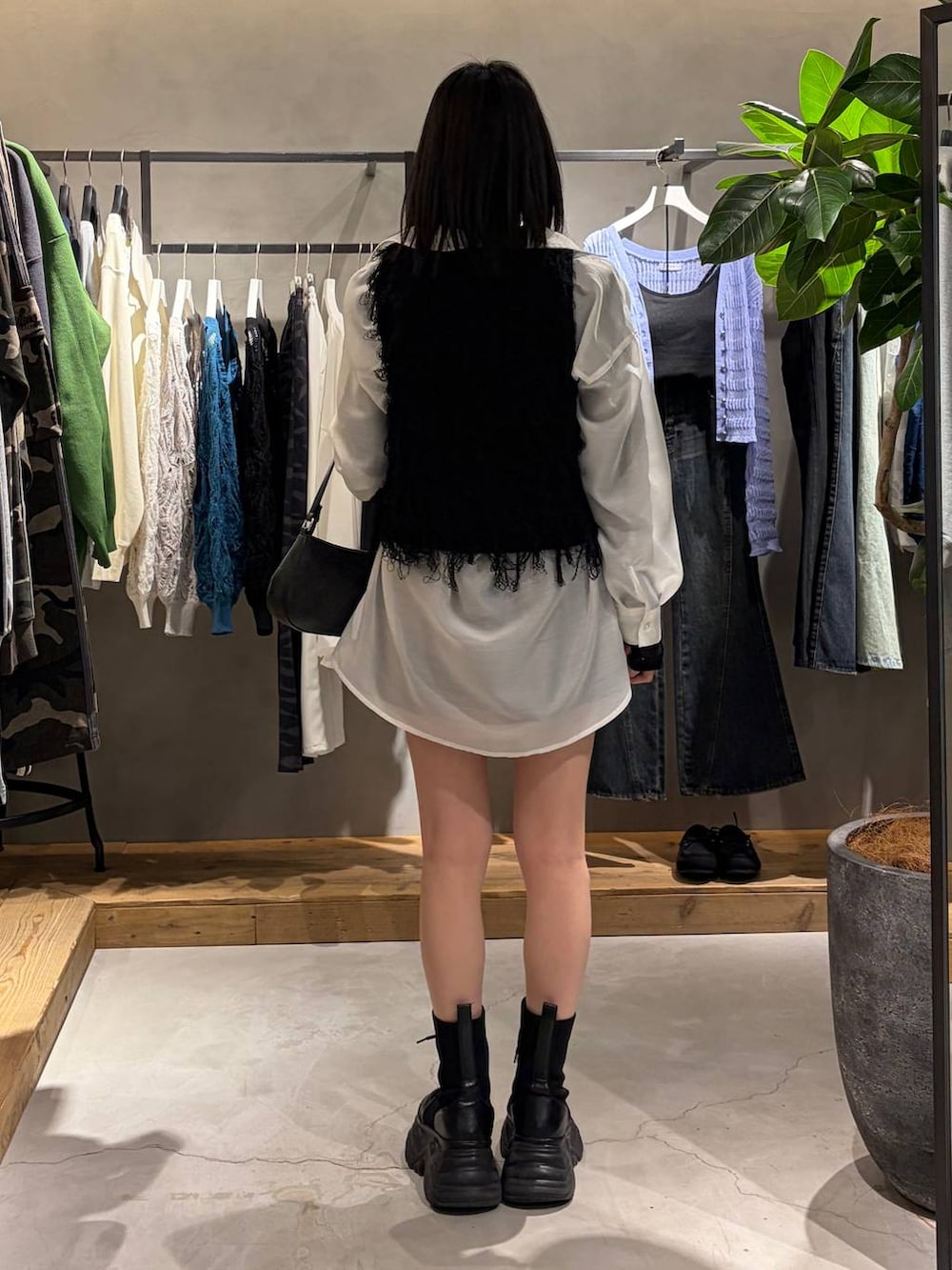 ブラック系のブーツ、ブラック系のハンドバッグ、ブラック系のベストを着用したレディースの春コーディネートの3枚目の写真