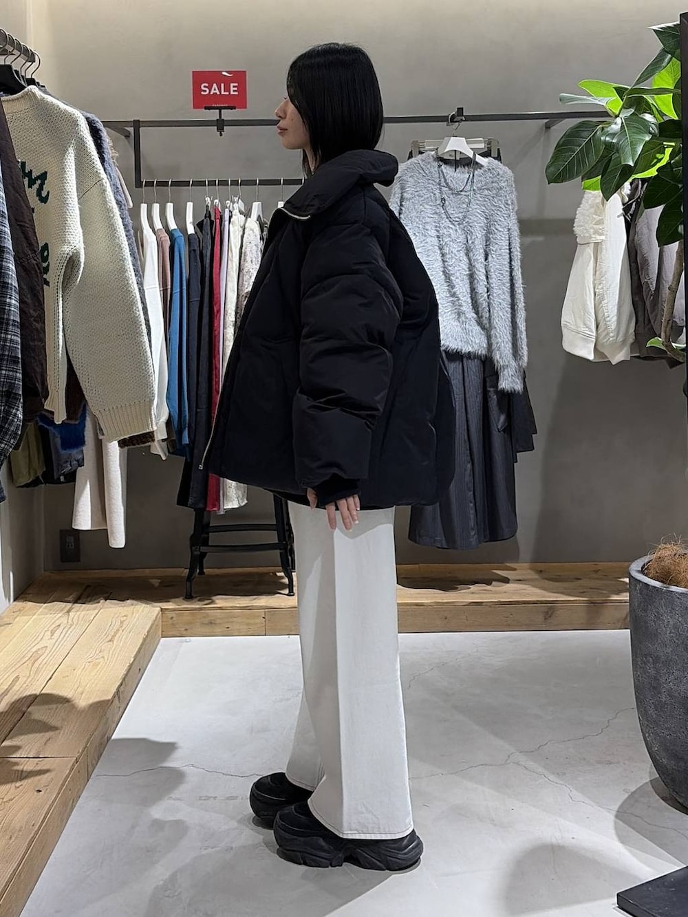 ブラック系のブーツ、ブラック系のブルゾン、ホワイト系のスラックスを着用したレディースの冬コーディネートの2枚目の写真