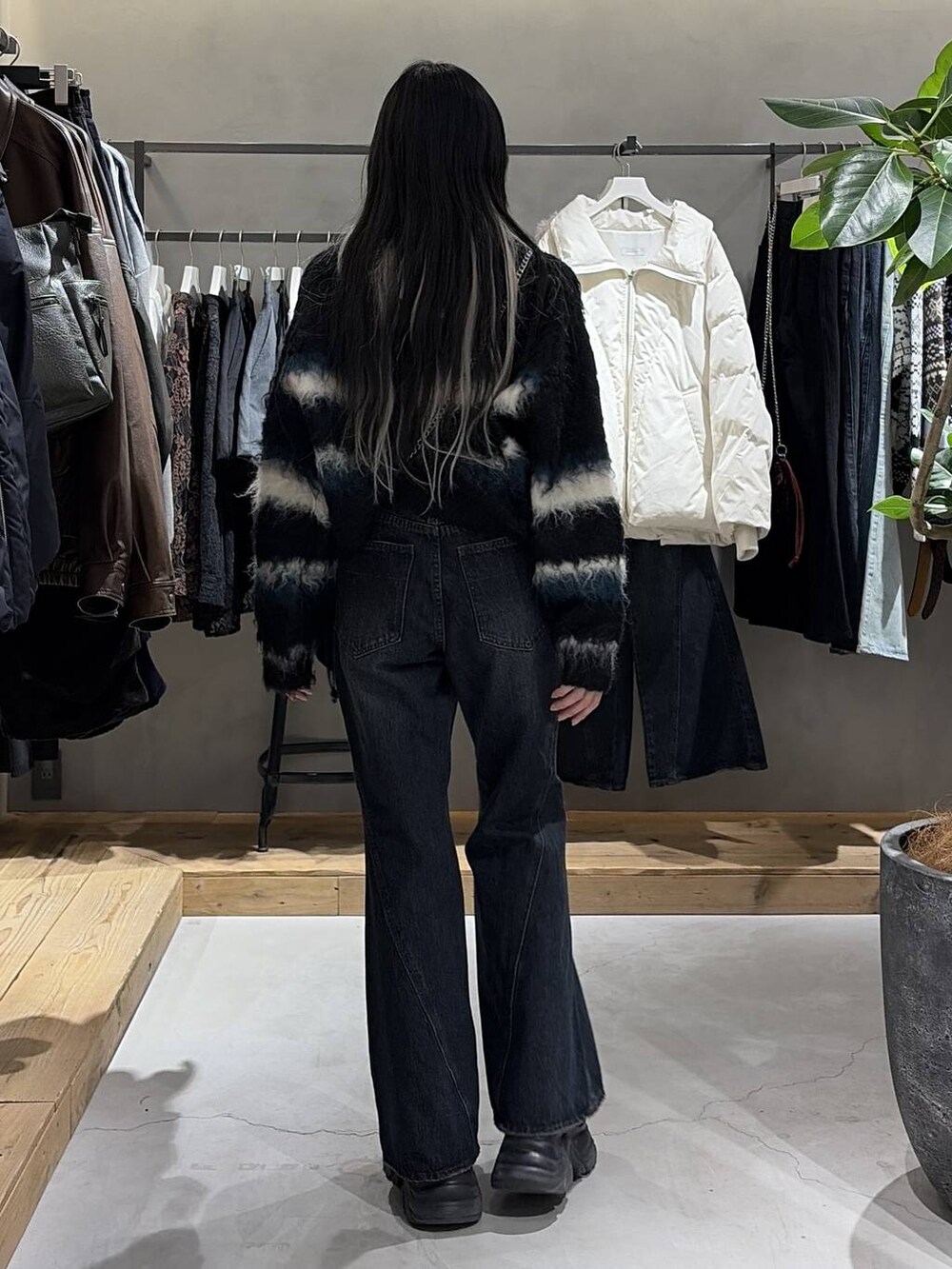 ブラック系のブーツ、ブルー系のデニムパンツ、ブラック系のハンドバッグを着用したレディースの冬コーディネートの3枚目の写真