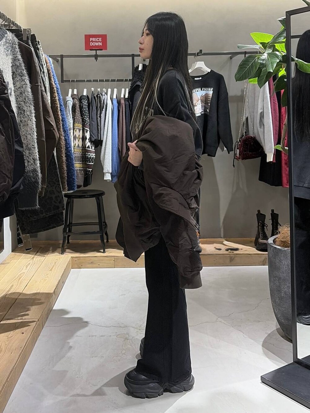 ブラック系のブーツ、ブラック系のデニムパンツ、グレー系のスウェットを着用したレディースの冬コーディネートの2枚目の写真